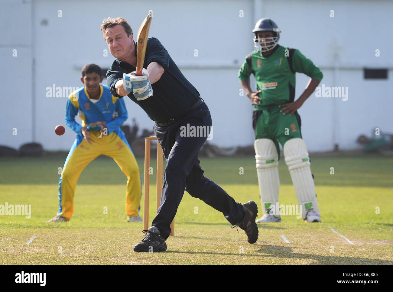 Prime Minister David Cameron faces the bowling of Sri Lankan cricketer Muttiah Muralitharan at Colombo's National Cricket Academy where the former bowler runs a charity bringing young people from both sides of the Sri Lankan communities together by playing cricket, during his visit to Sri Lanka to attend the Commonwealth Heads of Government Meeting. Stock Photo