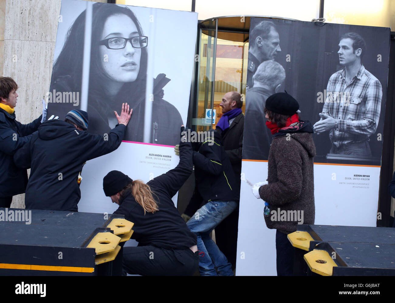 Greenpeace demonstrators move photographs of Alexandra Harris and Kieron Bryan as they set up an exhibition entitled 'Thirty Acts of Courage' featuring giant portraits of the activists arrested in Russia as part of the group's continuing campaign against drilling in the Arctic, outside the Shell building on the Southbank, central London. Stock Photo
