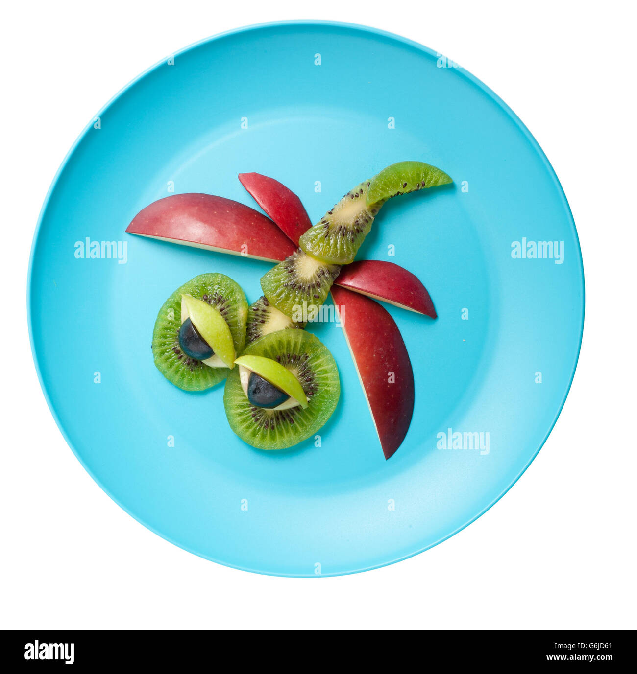 Dragonfly made of kiwi and apple on blue plate Stock Photo