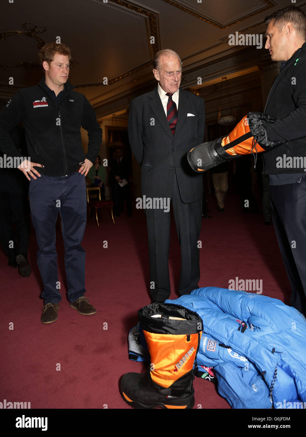 The Duke of Edinburgh (centre) and Prince Harry (left) look at a boot shown to them by a member of Team USA, during a reception to meet the three teams of wounded servicemen and women from the United Kingdom, the United States and the Commonwealth, ahead of the Walking With The Wounded South Pole Allied Challenge, at Buckingham Palace in central London. Stock Photo