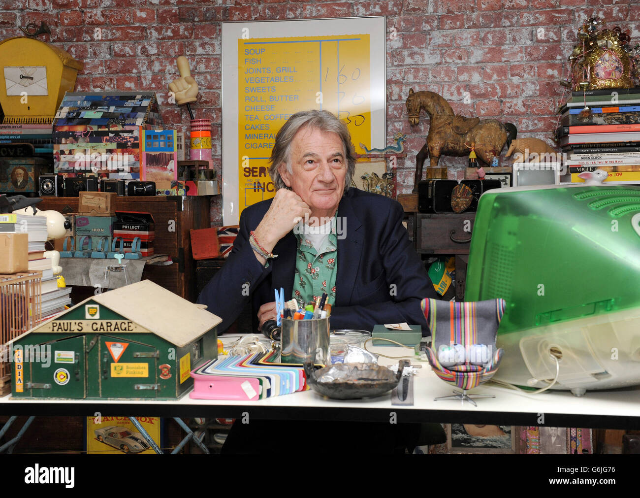 Fashion Designer Paul Smith poses for photographs in a replica of one of his original working spaces at the opening of his new exhibition 'Hello, My Name is Paul Smith' at the Design Museum, London. The exhibition features hundreds of objects from the designers personal archive, including photographs, objects and many of his clothing designs from throughout his career. Stock Photo