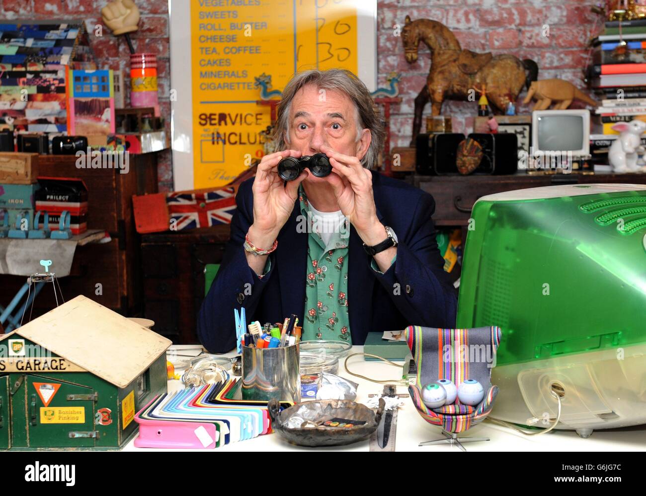 Fashion Designer Paul Smith poses for photographs in a replica of one of his original working spaces at the opening of his new exhibition 'Hello, My Name is Paul Smith' at the Design Museum, London. The exhibition features hundreds of objects from the designers personal archive, including photographs, objects and many of his clothing designs from throughout his career. Stock Photo