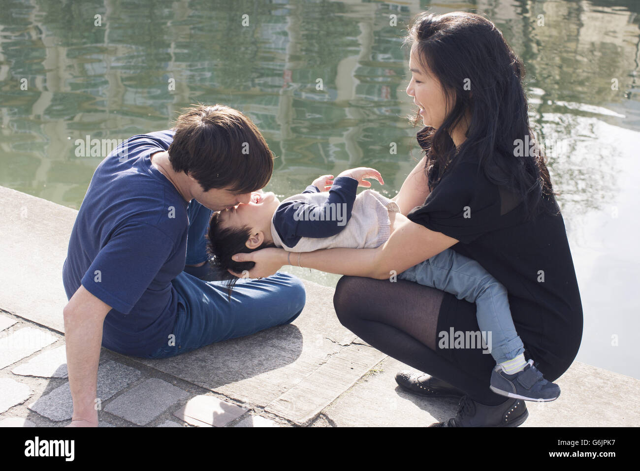 Parents and little boy playing on riverbank Stock Photo