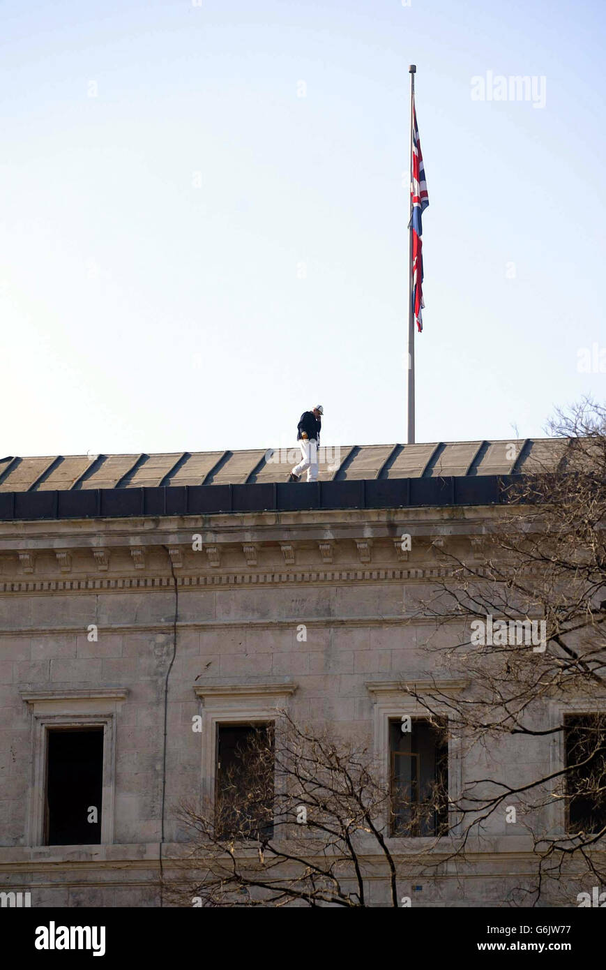 The Union Jack drapes from the pole on top of the British Consulate building where a Turkish police forensic officer inspects the roof, in Istanbul, following yesterday's terrorist bombings in the city. Stock Photo