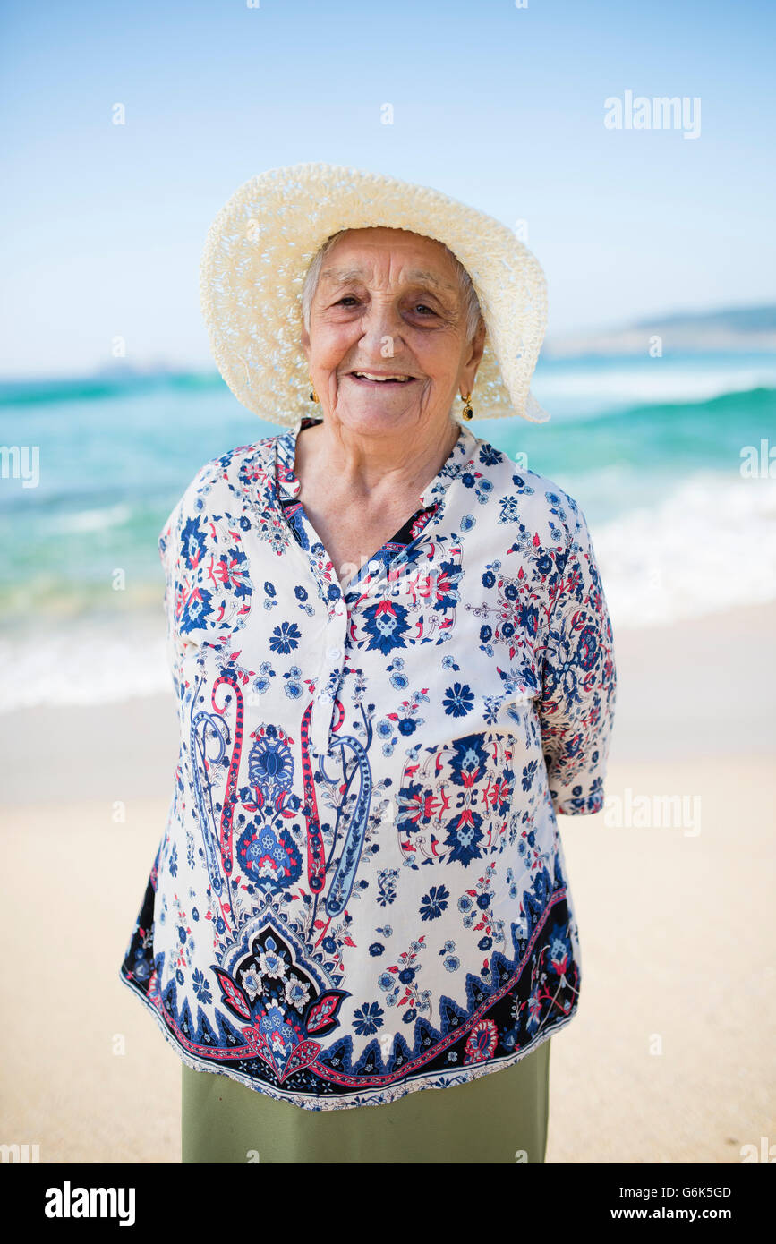 Portrait of smiling senior woman standing on the beach Stock Photo - Alamy