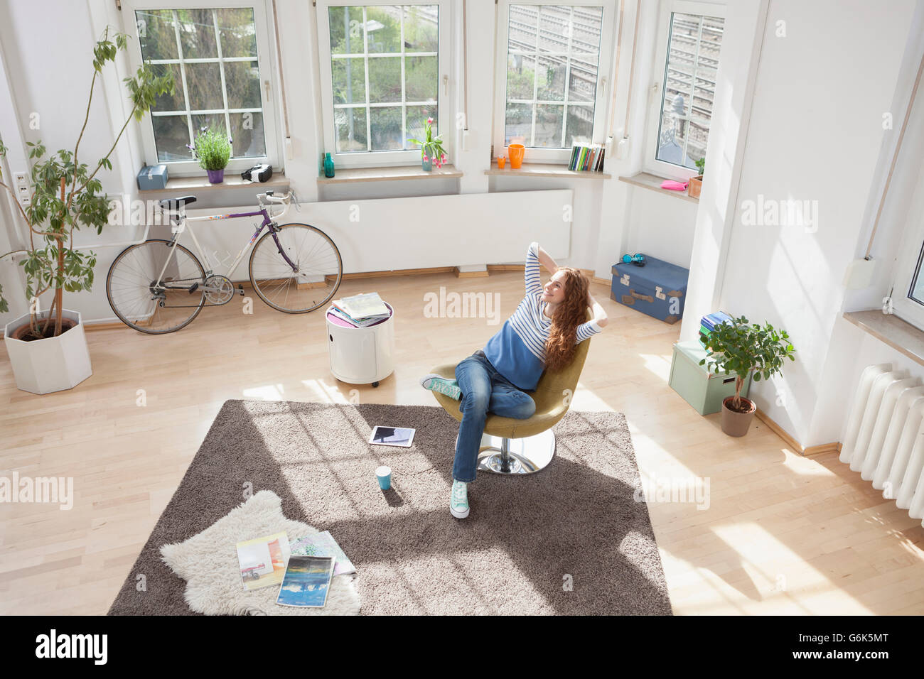 Relaxed woman at home sitting in chair Stock Photo