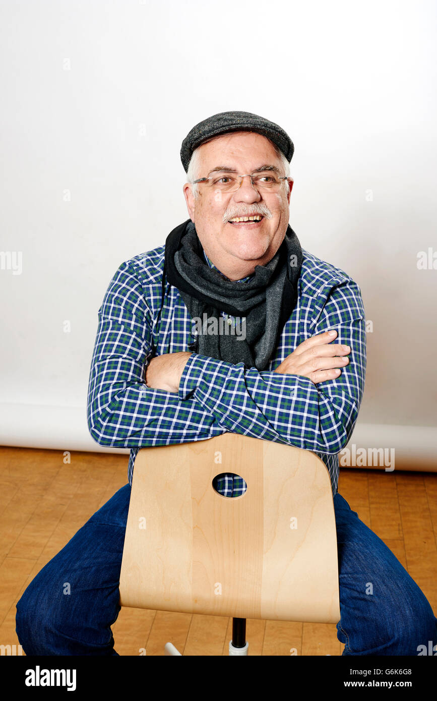 Portrait of smiling senior man sitting backwards on a chair Stock Photo