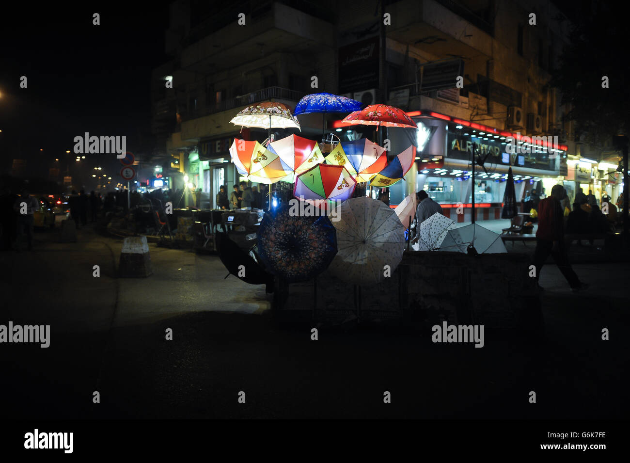An umbrella vendor's stall is lit up at night on the streets of Baghdad, Iraq. Stock Photo