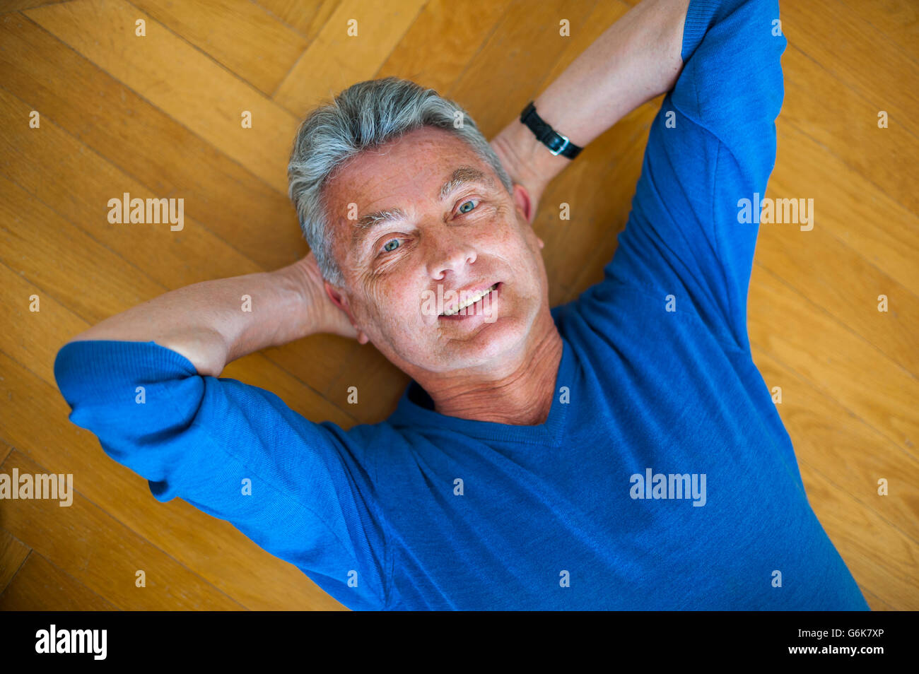 Portrait of smiling senior man lying on parquet floor Stock Photo - Alamy
