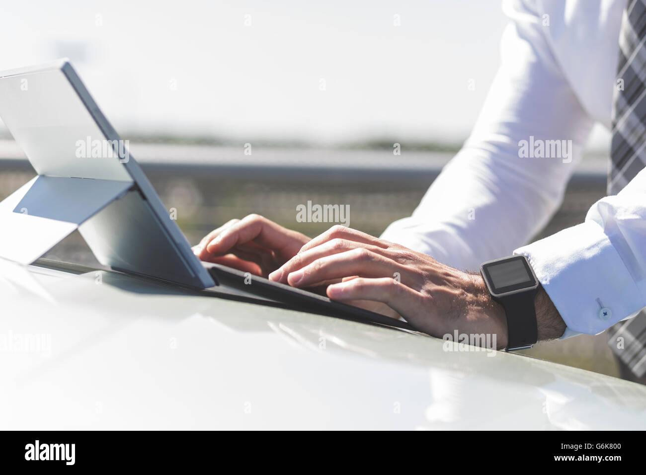 Businessman using digital tablet on car bonnet Stock Photo