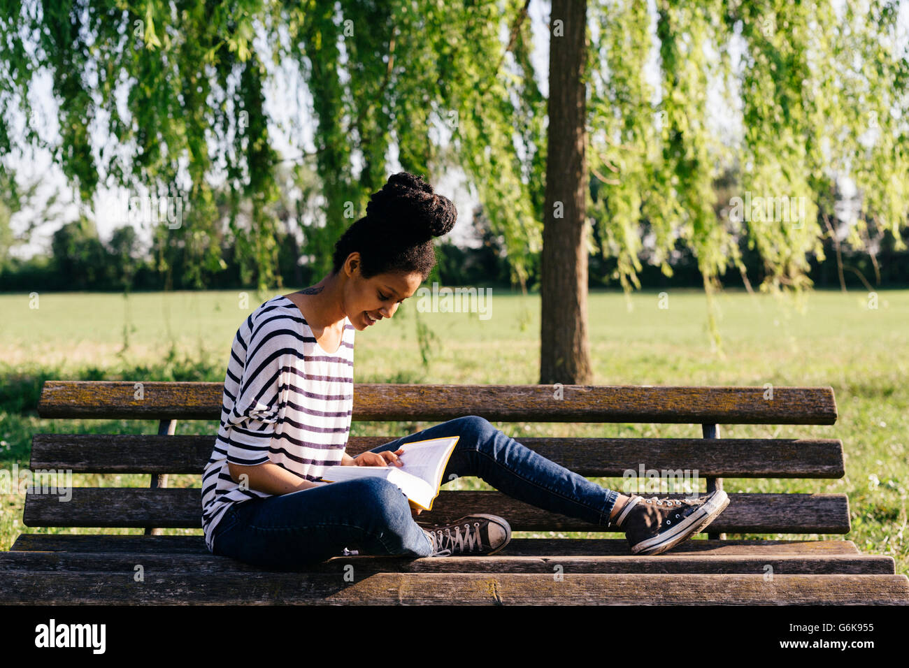 young-woman-sitting-on-park-bench-reading-a-book-stock-photo-alamy