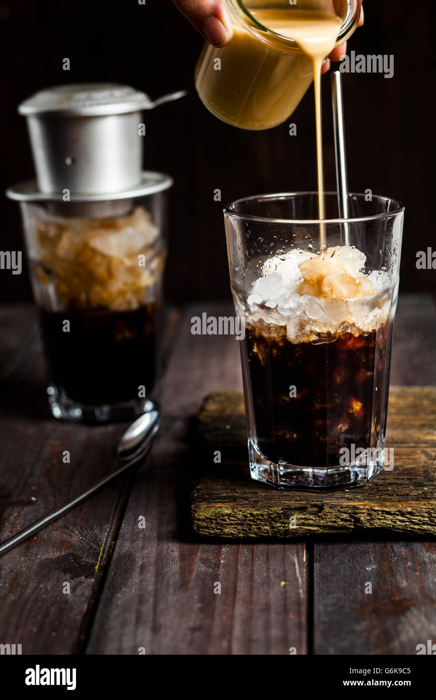 Pouring sweetened condensed milk over vietnamese iced coffee Stock