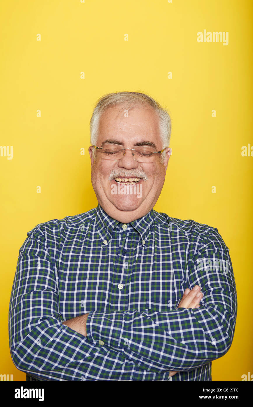 Portrait of smiling senior man with arms crossed and eyes closed in ...