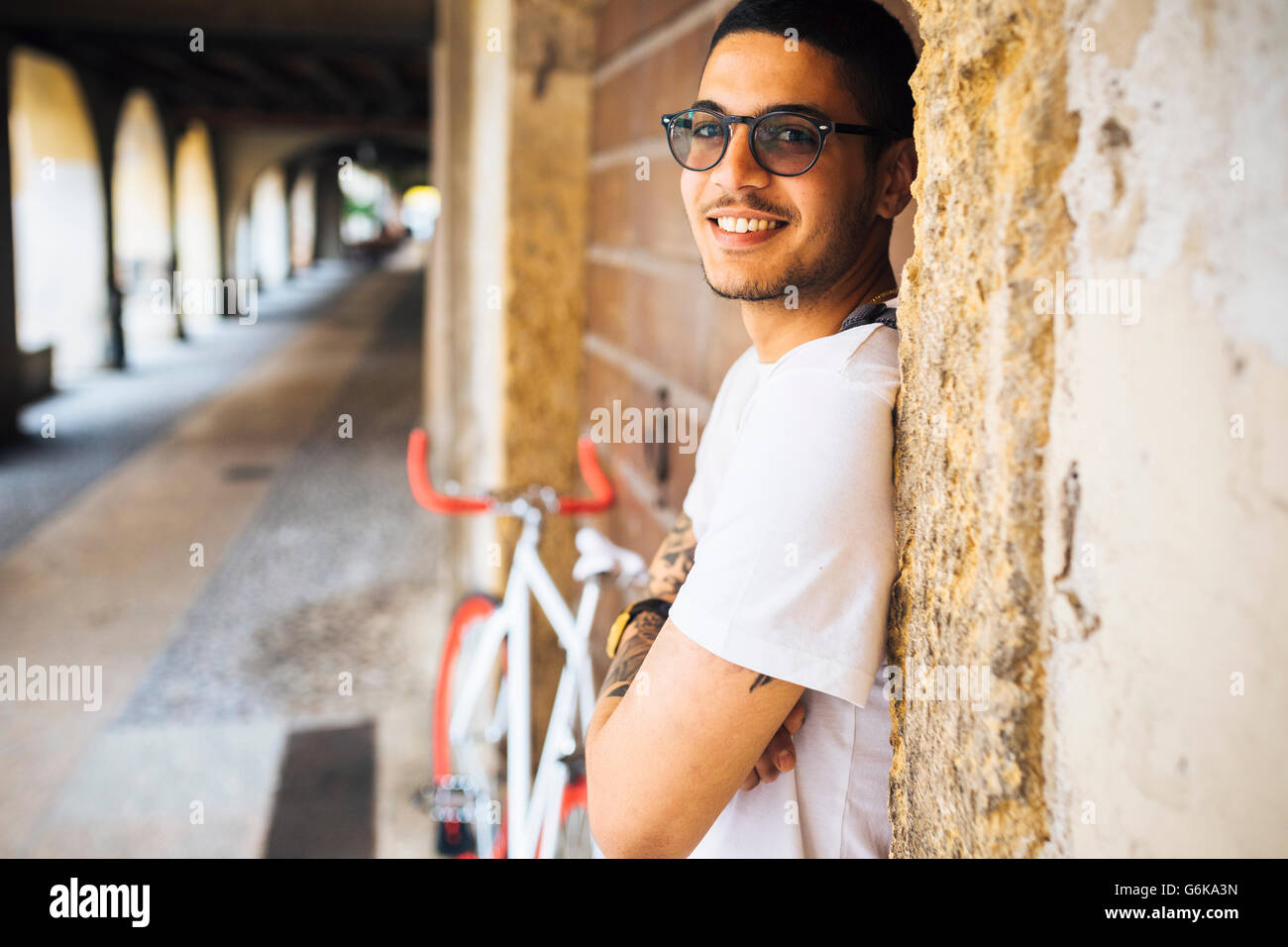 Young man with sunglasses leaning against a wall Stock Photo - Alamy