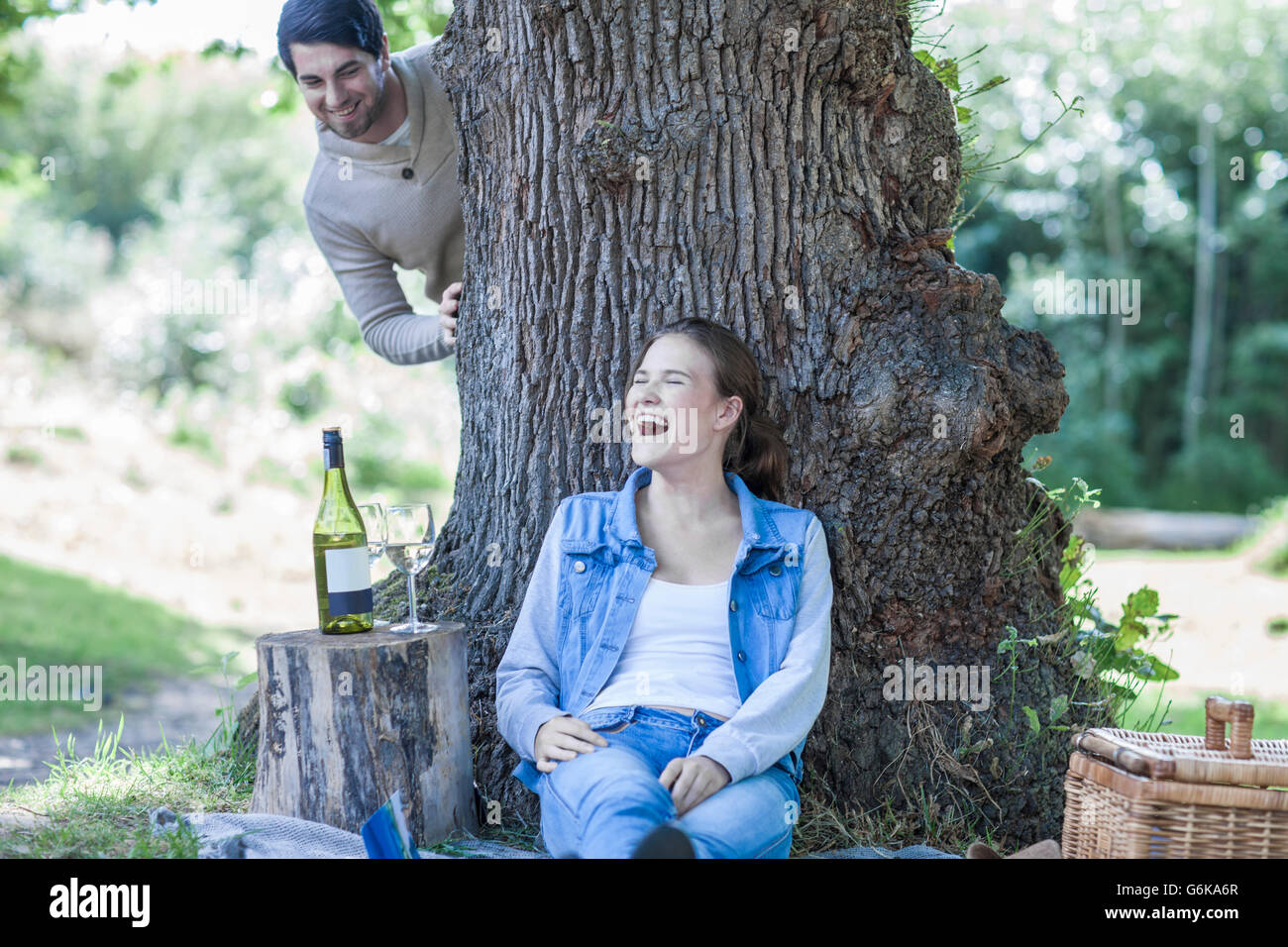 Playful young couple having a picnic with white wine Stock Photo - Alamy