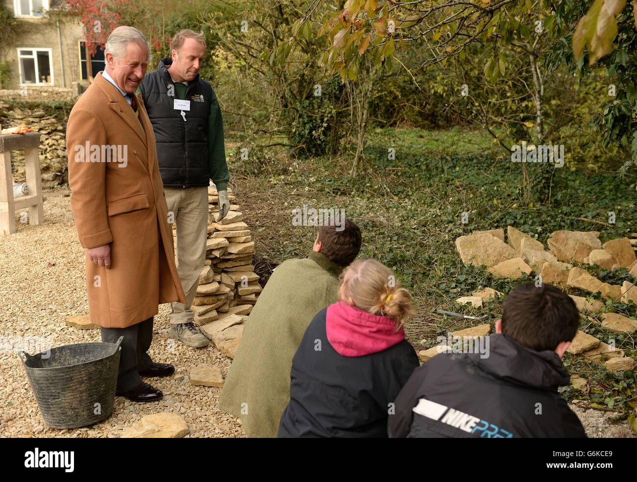 The Prince of Wales (left) is given a demonstration by Jon Bendle (second left) and students on building a dry stone wall during a visit to the Royal Agricultural University's Rural Innovation Centre at Manor Farm in Gloucestershire. Stock Photo