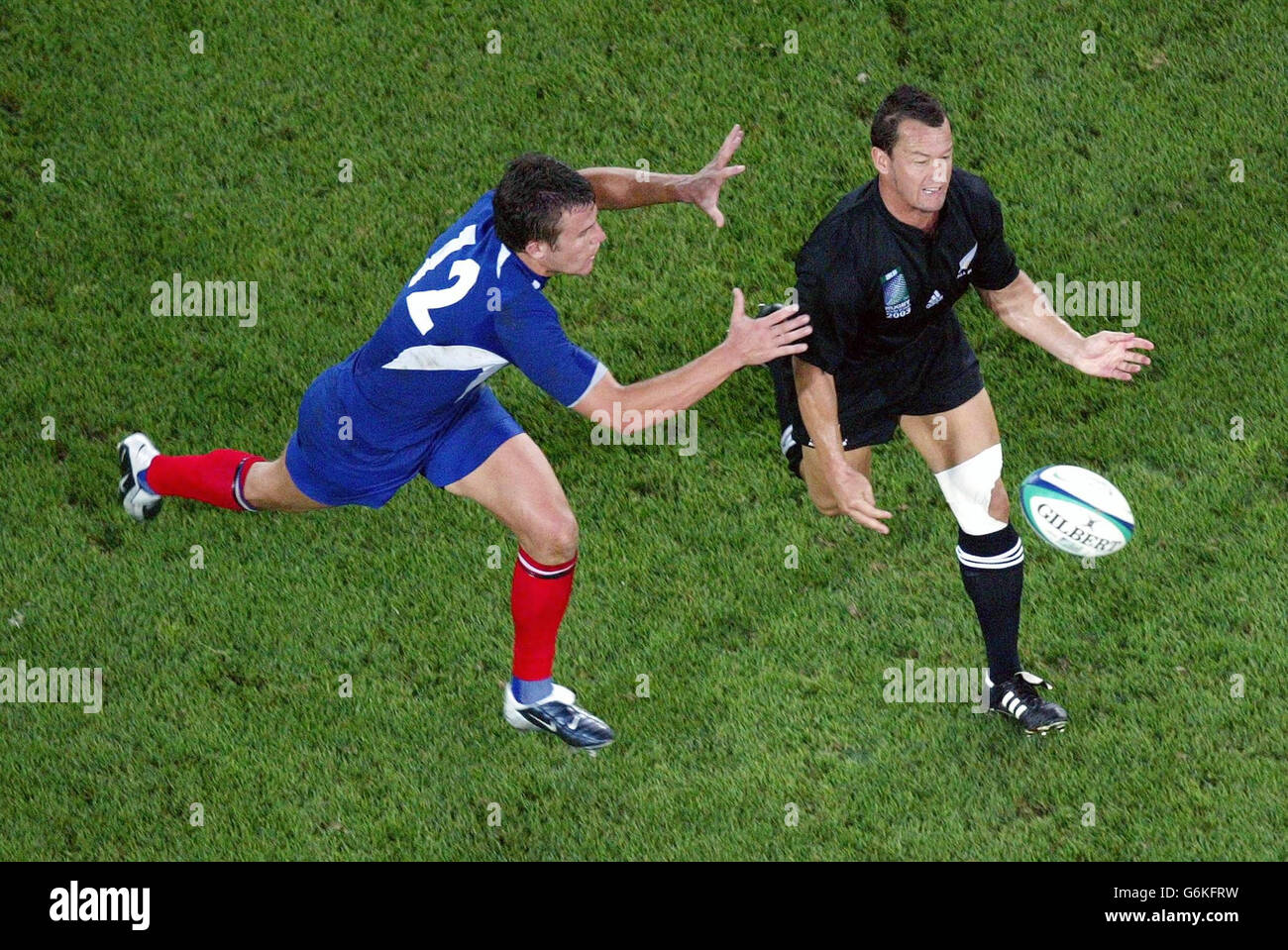 New Zealand's Carlos Spencer gets his pass away as he is tackled by Damien Traille of France during their 40-13 victory over France in the Rugby Union World Cup 3rd place playoff match at Telstra Stadium, Sydney. Stock Photo