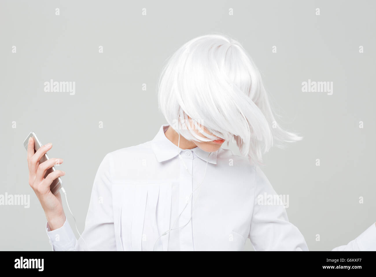 Attractive young woman with blonde hair listening to music from cell ...