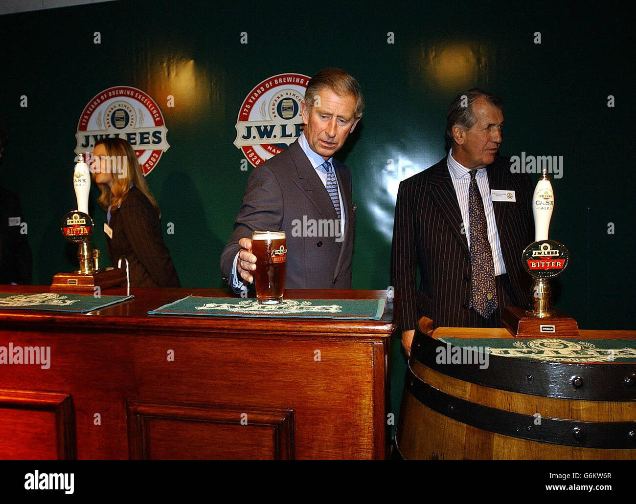 The Prince of Wales picks up a pint of beer from behind the bar during a visit to the JW Lees Brewery at Middleton near Manchester. Members of the Lees-Jones family, who still run the brewery, met the Prince at the entrance before taking him on a tour to celebrate its 175th anniversary. Stock Photo