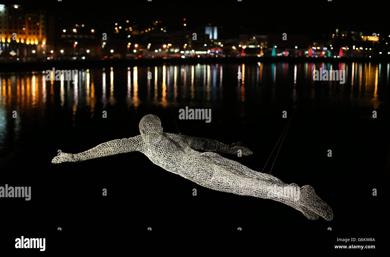A figure from the series called 'The Travellers' by Cedric Le Borgne, overlooking the peace bridge in Londonderry as the Lumiere festival opens as part of the UK City of Culture celebrations. Stock Photo