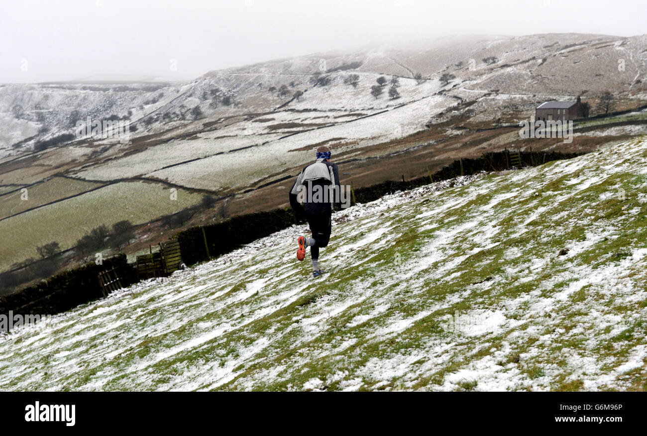 A runner braves the condition with snow on the hilltops around Buxton in the Peak District. Stock Photo