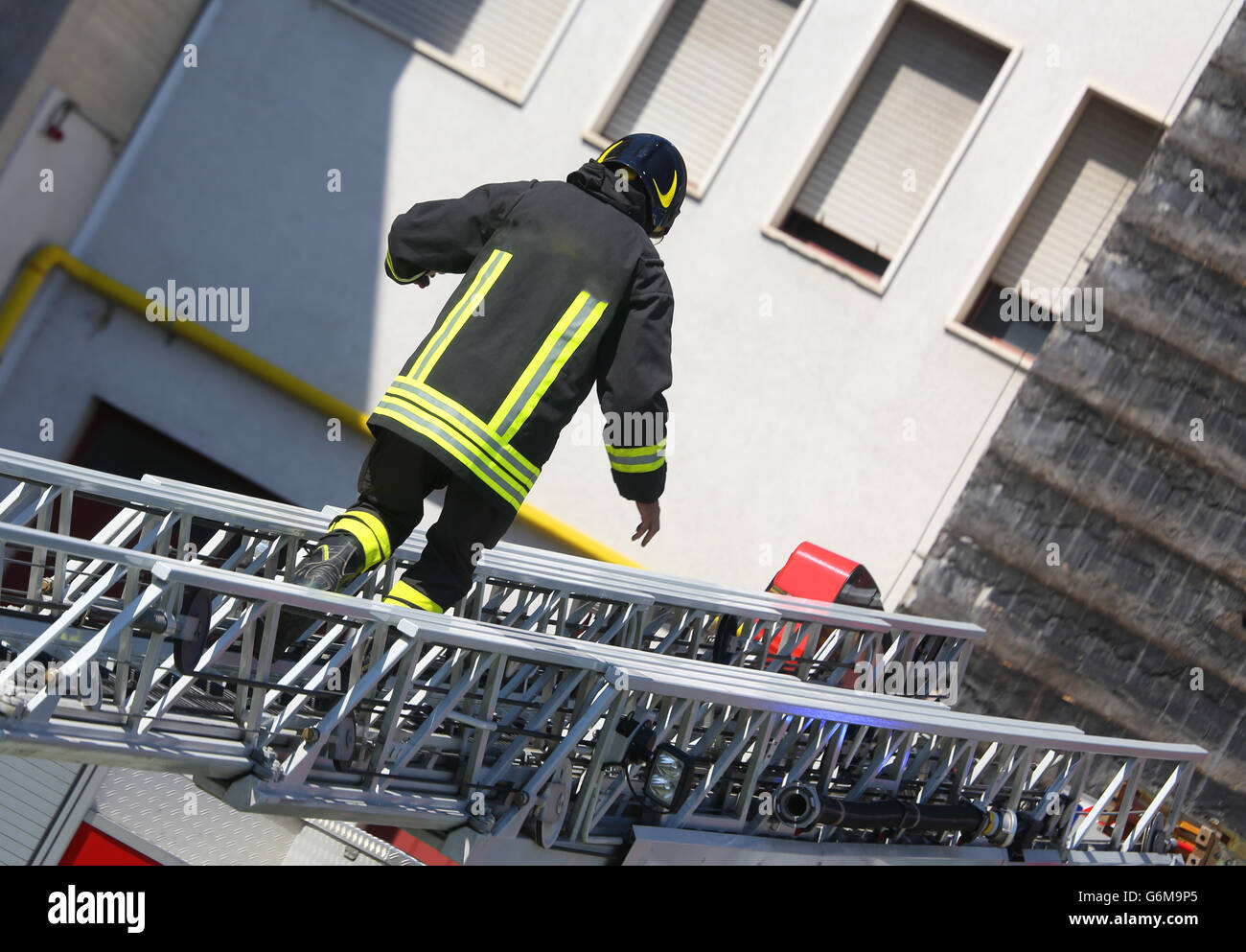 brave firefighter walks on extended ladder of firetrucks during the fire Stock Photo