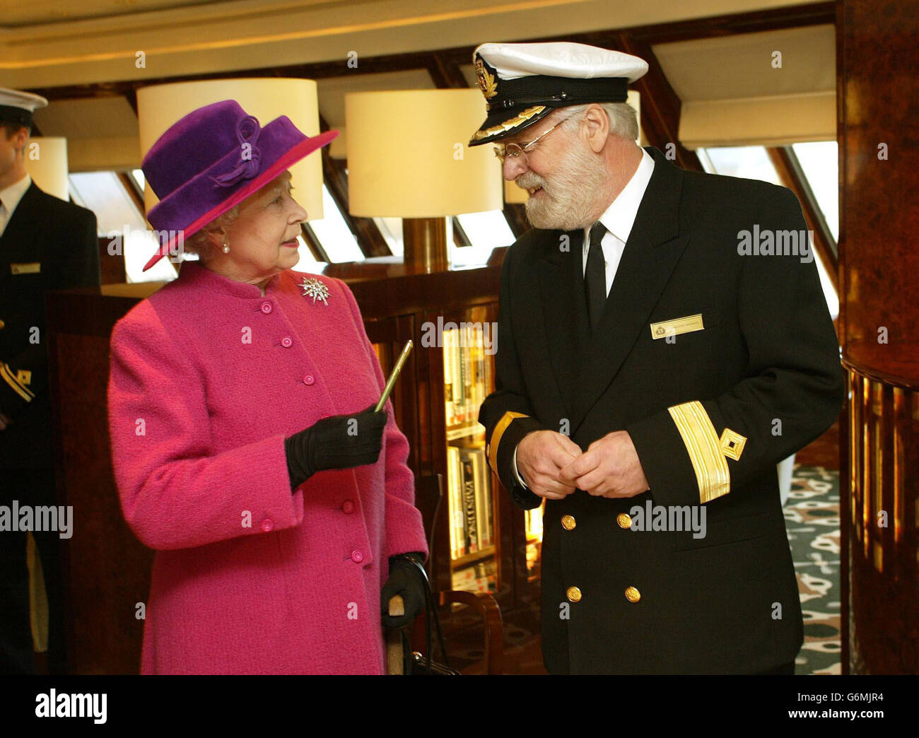 Queen Elizabeth II holds a pen made from part of a propeller on the original Queen Elizabeth ship, as she talks to Commador Ronald Warwick on the bridge of the Queen Mary 2 cruise liner in Southampton Docks, before naming the 550 million vessel in front of more than 2,000 guests. It was the first time the Queen had named a Cunard ship since the launch in 1967 of the QE2, whose Southampton to New York service will be taken over by the 2,620-passenger QM2 in April. Stock Photo