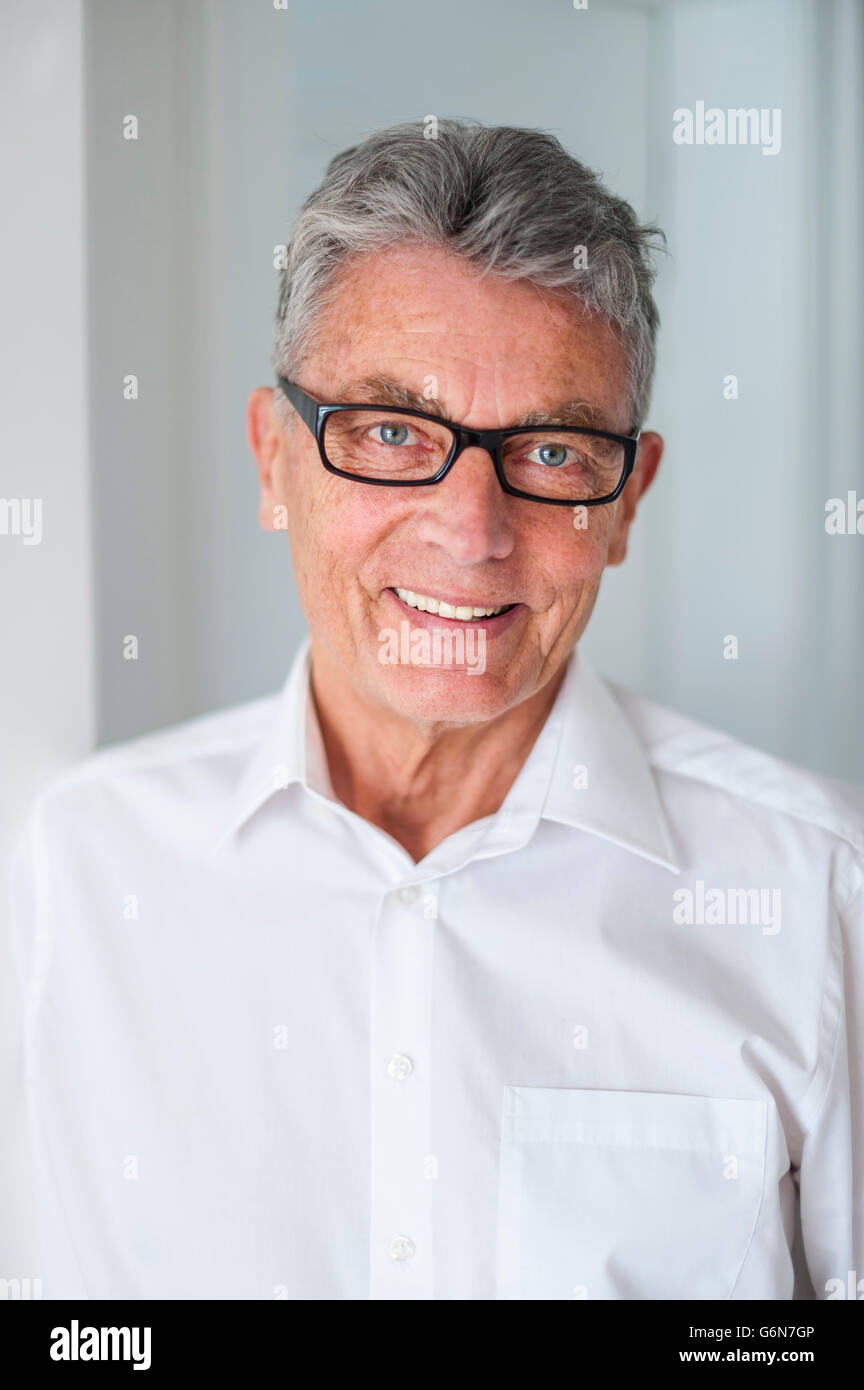 Portrait of smiling senior man wearing glasses and white shirt Stock Photo