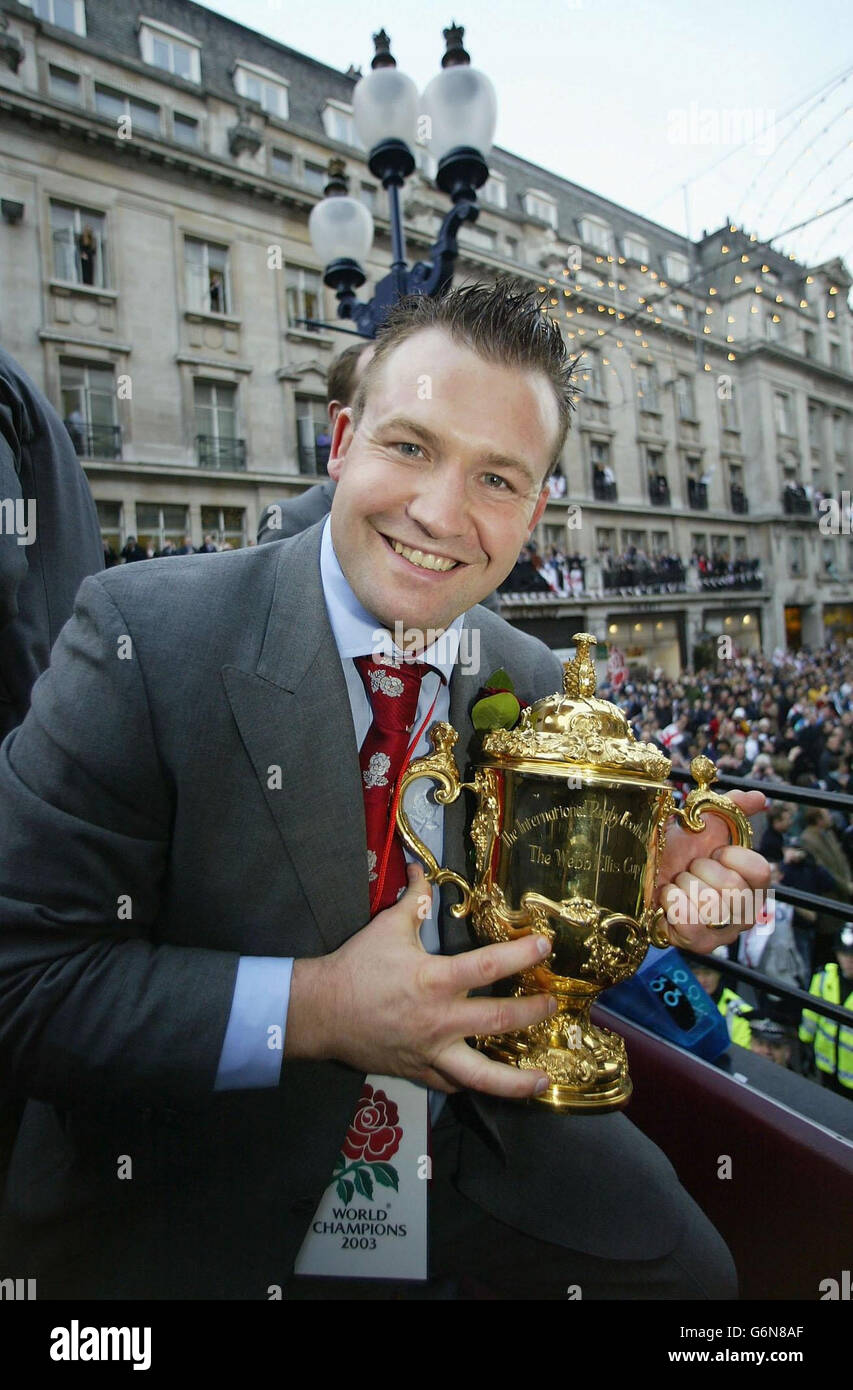 England player Mark Regan holds the Webb Ellis Cup during the England Rugby World Cup team victory parade in central London. The two open-topped buses arrived outside the National Gallery to a rapturous welcome from thousands of fans. The square was a sea of red and white flags as the nation's heroes waved to fans. Stock Photo