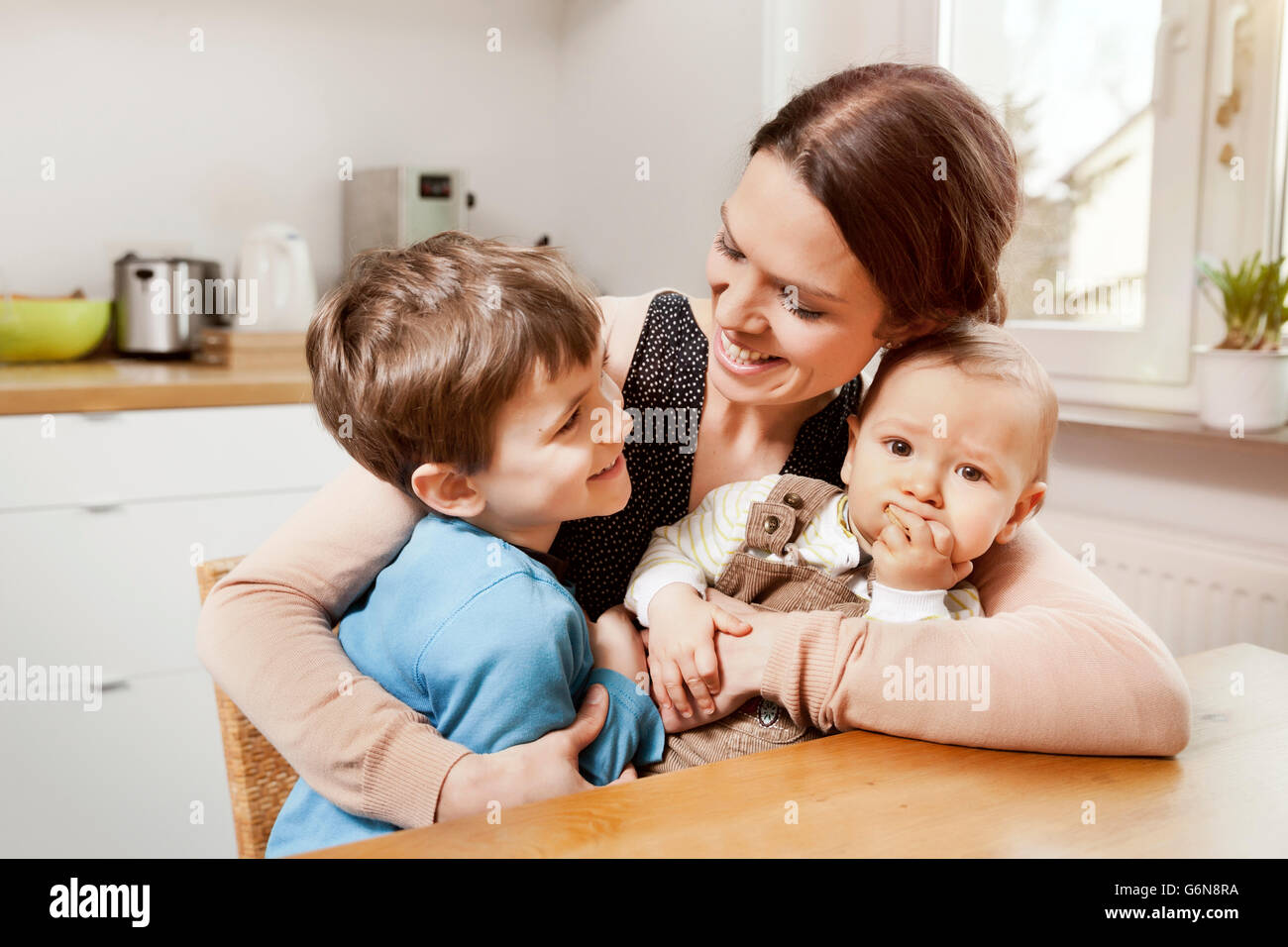 Happy mother with her little sons in the kitchen Stock Photo