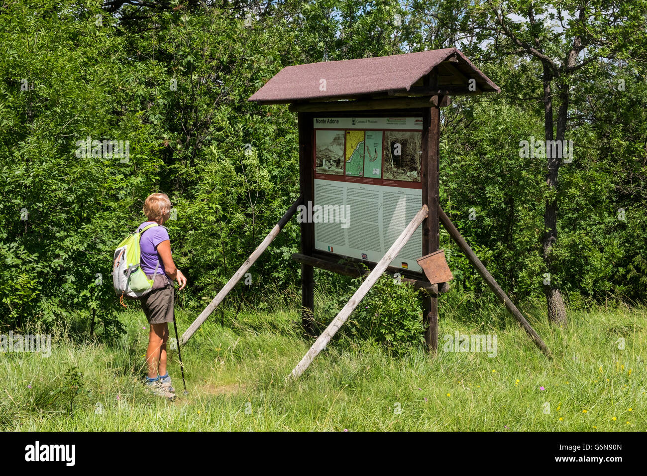 Woman walker reading the information panel describing the events that happened in the Monzuno area during World war 2, Monte Ado Stock Photo