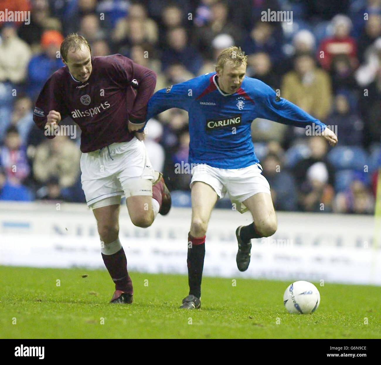 : Hearts player Neil MacFarlane (left) attempts to tackle Rangers Stephen Hughes, during their Bank of Scotland Scottish Premiership match at Rangers' Ibrox Stadium in Glasgow. Final score Rangers 2, Hearts 1. Stock Photo