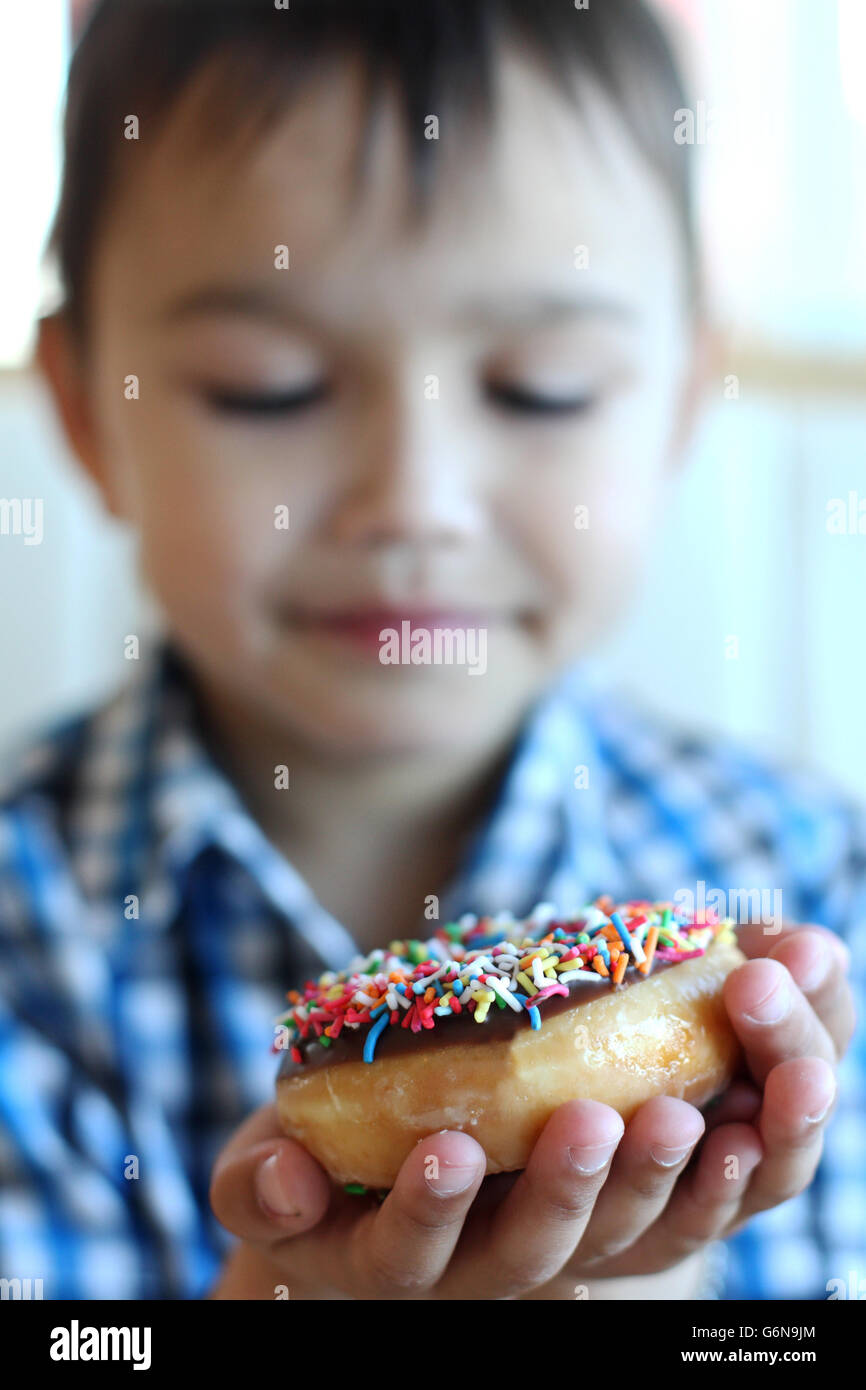 A child holding colorful sprinkle donut with donut in focus Stock Photo