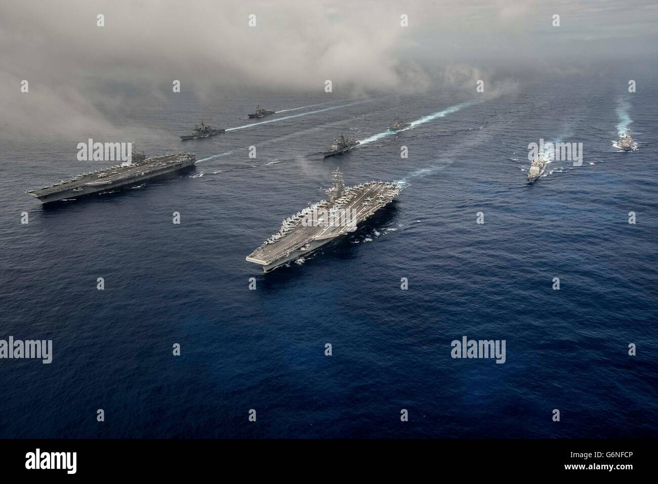 U.S Navy Nimitz-class nuclear-powered super-carrier USS John C. Stennis, left, and USS Ronald Reagan, right, steam in formation during dual operations June 18, 2016 in the Philippine Sea. Stock Photo