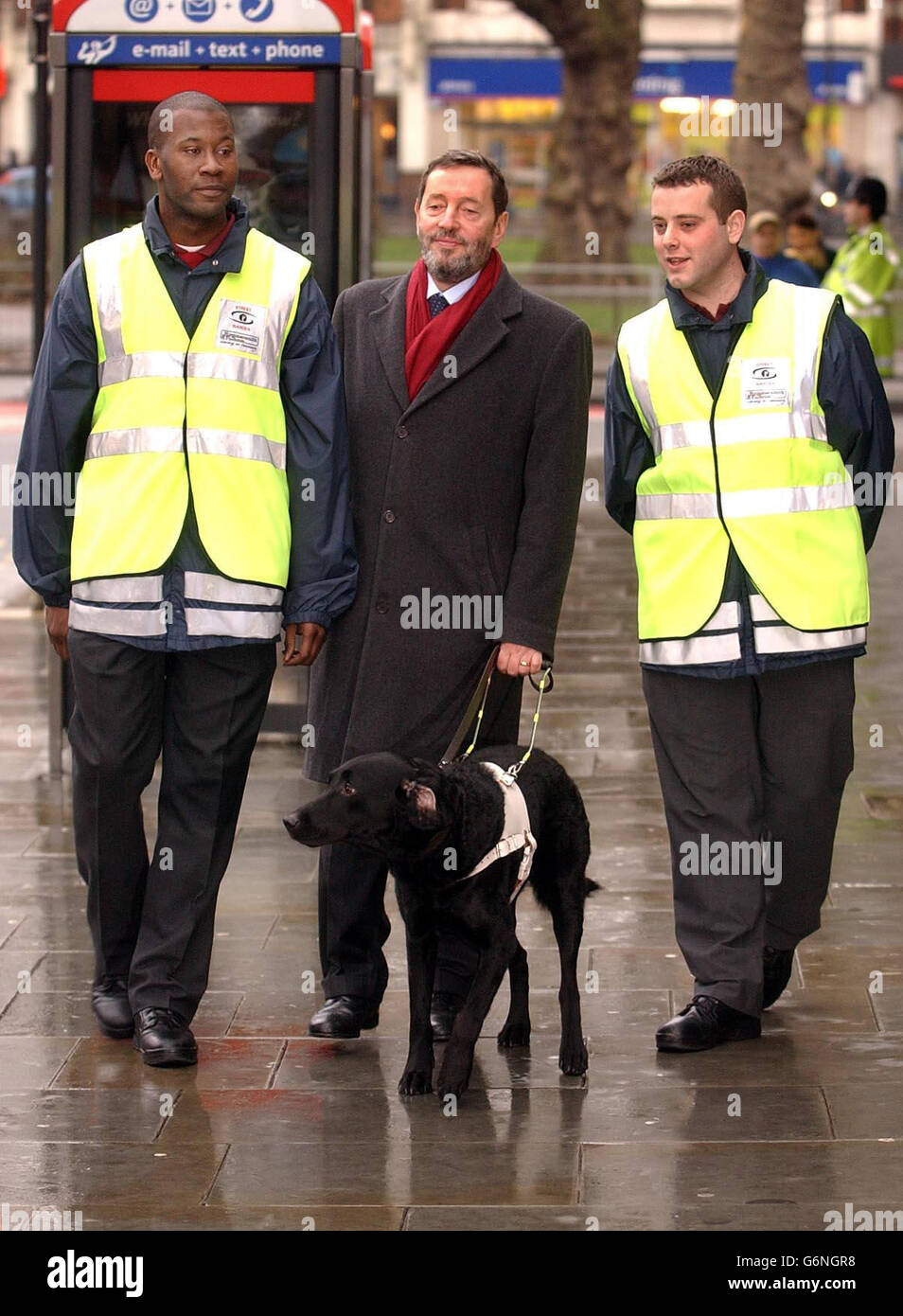 Home Secretary David Blunkett walks with Street Wardens Simeon Whatford (Right) and Sean Mullins (Left) in Shepherd's Bush, west London, as the Government launched new a new law to crack down on anti-social behaviour. Under new powers, police officers will be able to close down crack houses within 48 hours and keep them shut for up to six months and accredited private security guards will be able to stop cyclists for riding on the pavement. Stock Photo