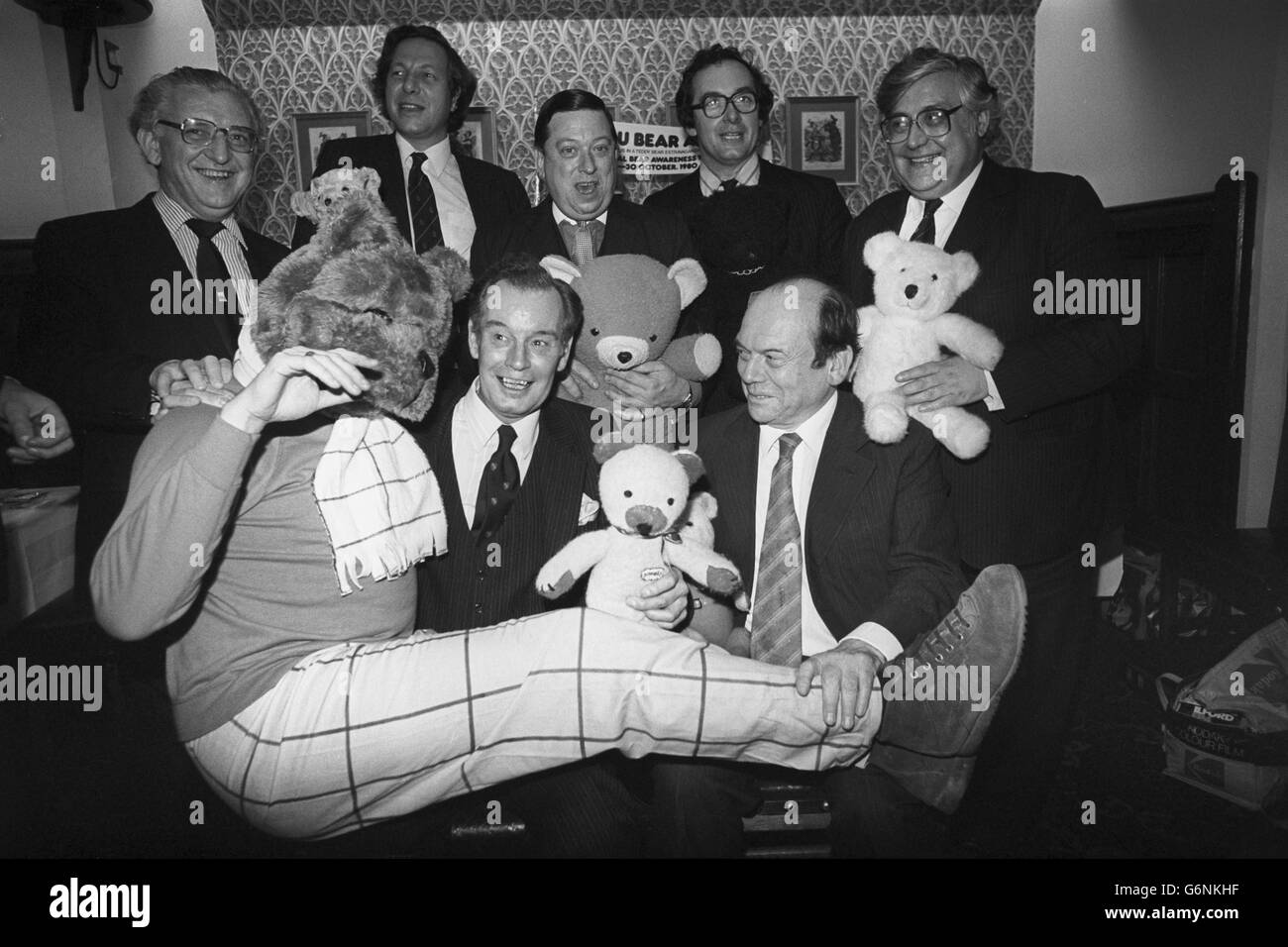 British MPs with 'Robert Bear' attend a Good Bears of the World charity reception at the House of Commons in Westminster, London. (Back row, from l-r) Wyn Roberts, Parliamentary Under-Secretary of State for Wales and MP for Conway; Ian Grist, MP for Cardiff North; Michael Brotherton, MP for Louth; Robin Squire, MP for Hornchurch; and Donald Thompson, MP for Sowerby. The man dressed up as Rupert Bear lies across the laps of Michael Roberts (r), Parly Under-Secretary of State for Wales and MP for Cardiff North West, and David Bevan, MP for Birmingham Yardley. The first teddy bear had a Stock Photo