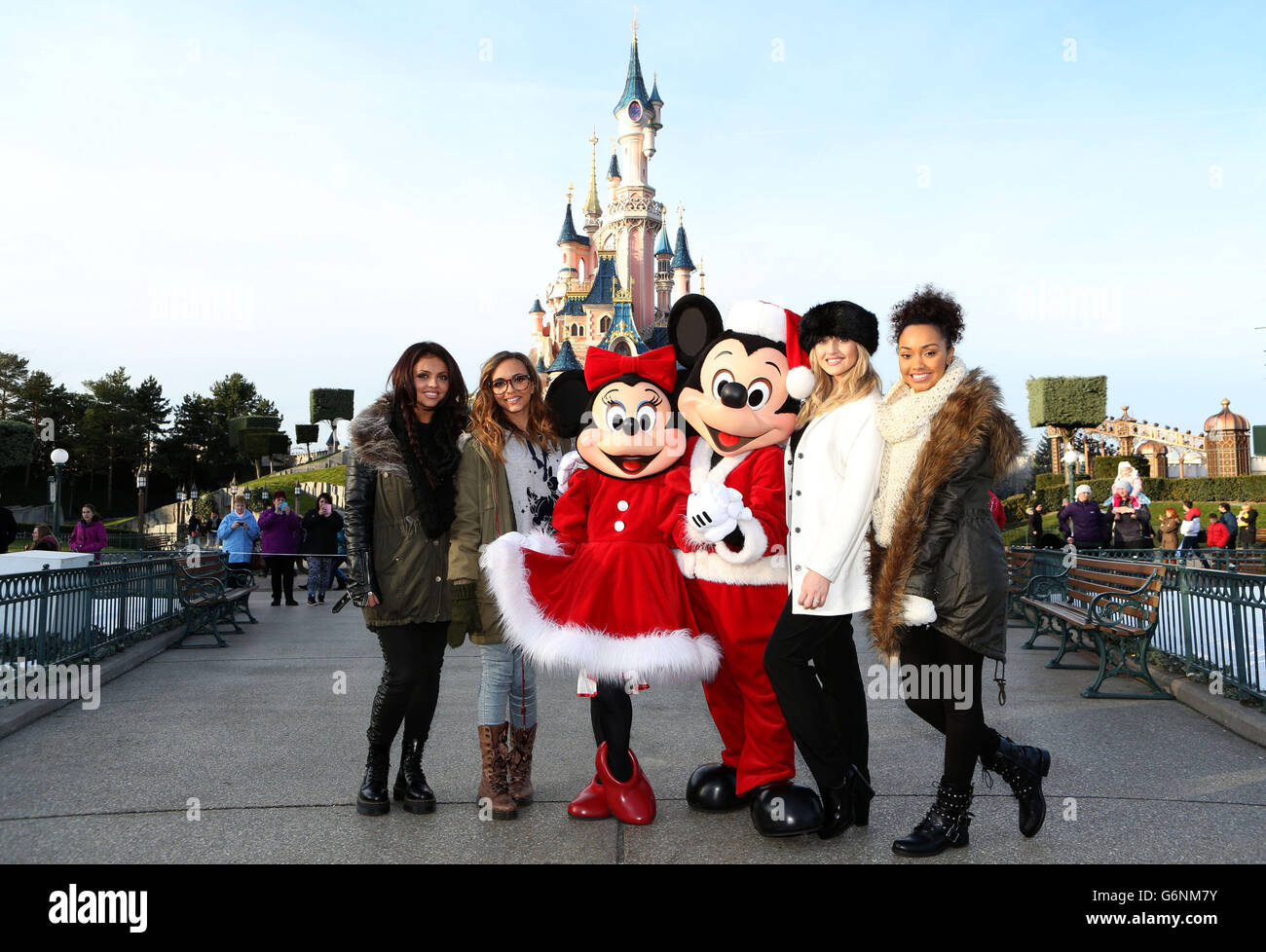 Jesy Nelson, Jade Thirlwall, Perrie Edwards and Leigh Anne Pinnock of Little Mix pose with Minnie and Mickey Mouse in front of the castle at Disneyland Paris as they accompany children from the Carers Trust and a community hub in a deprived area of east London on a charity day trip. Stock Photo