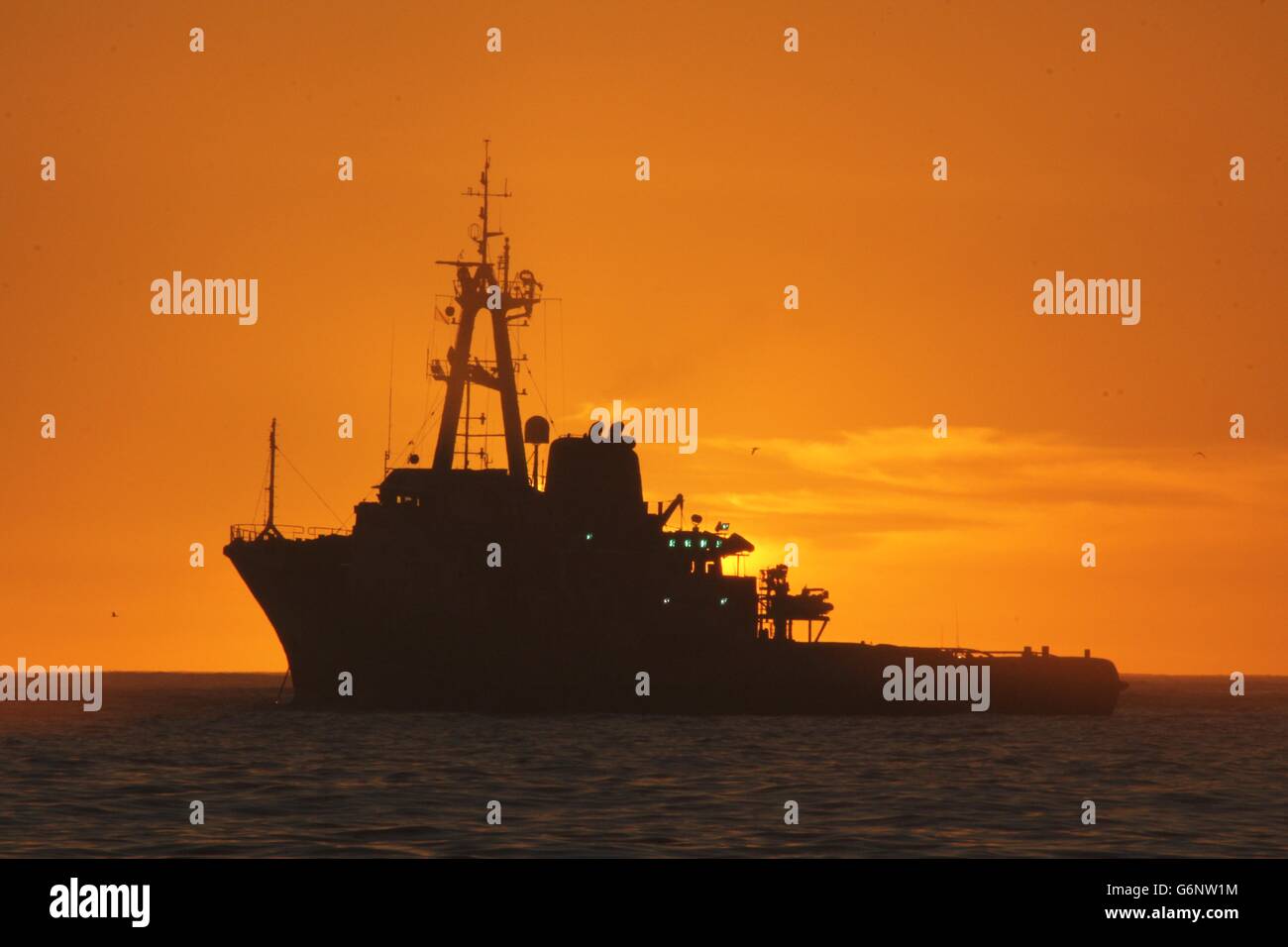 a large tugboat anchored in the sea at sunset Stock Photo
