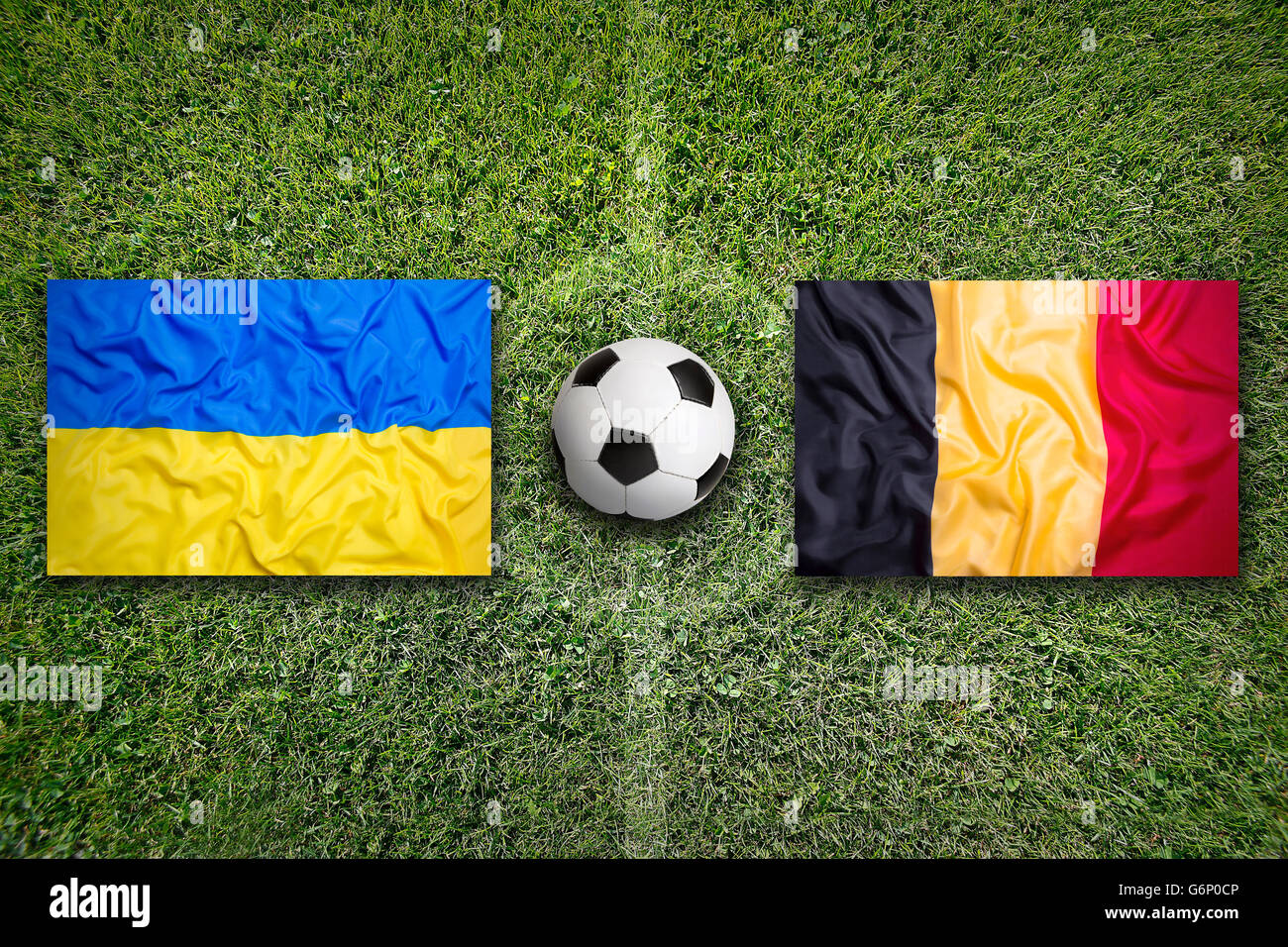 Ukraine vs. Belgium flags on green soccer field Stock Photo