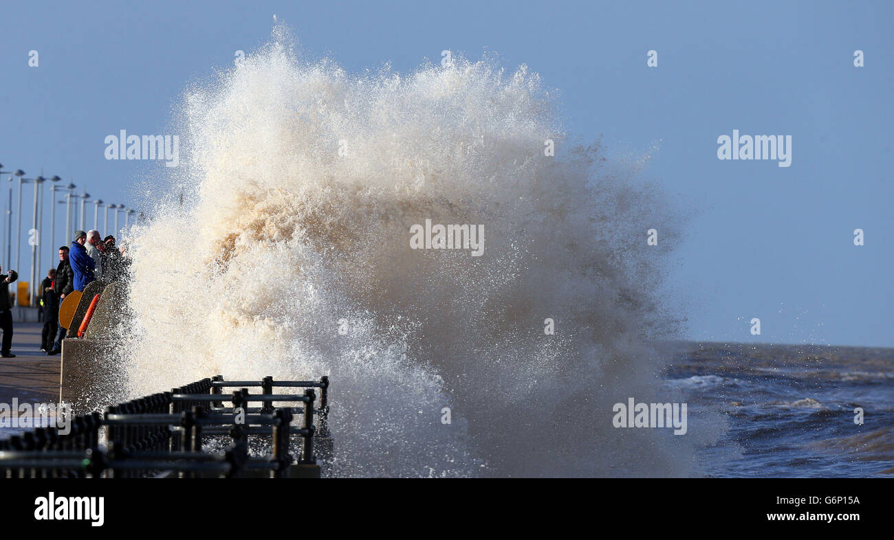 People watch as high waves crash over the sea front at New Brighton in Wirral, as heavy rain and strong winds sweep across the country. Stock Photo