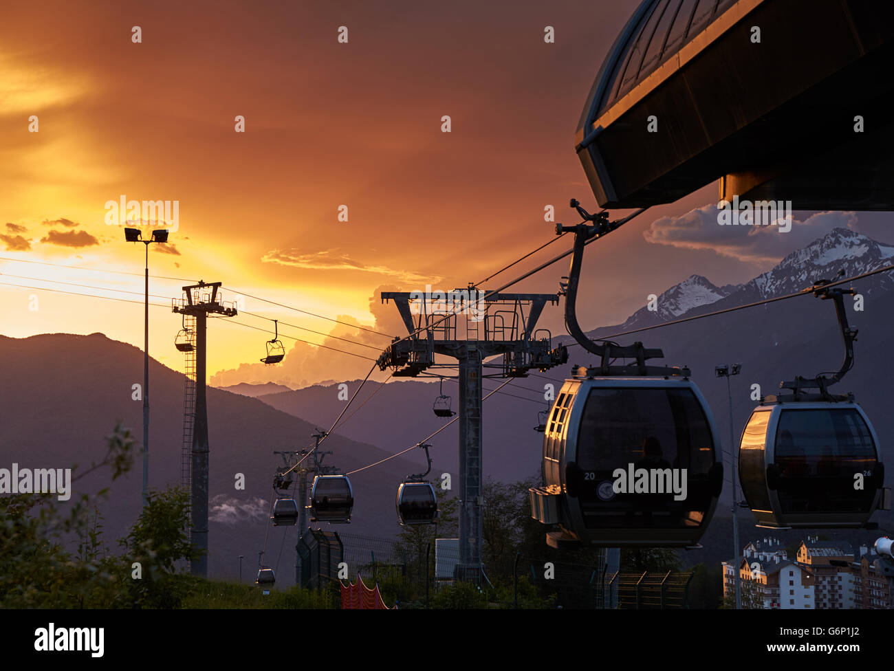 Ski lift, ropeway at sunset, the slopes of the ski resort Rosa Khutor, nobody, storm clouds, mountains peak, Caucasus, cable car Stock Photo