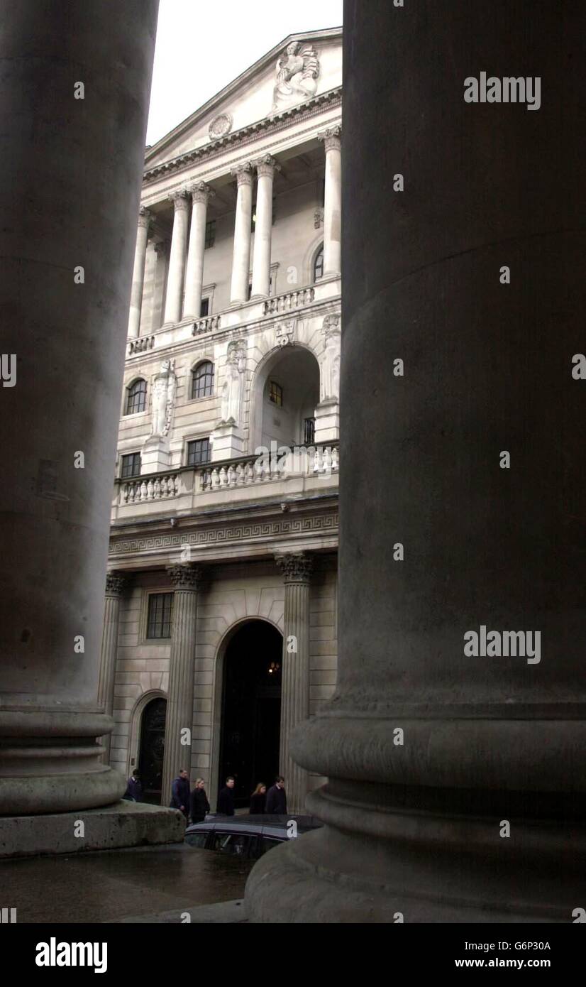 Workers bustle along past the Bank of England in the city of London, seen through two pillars of the Royal Exchange. Stock Photo