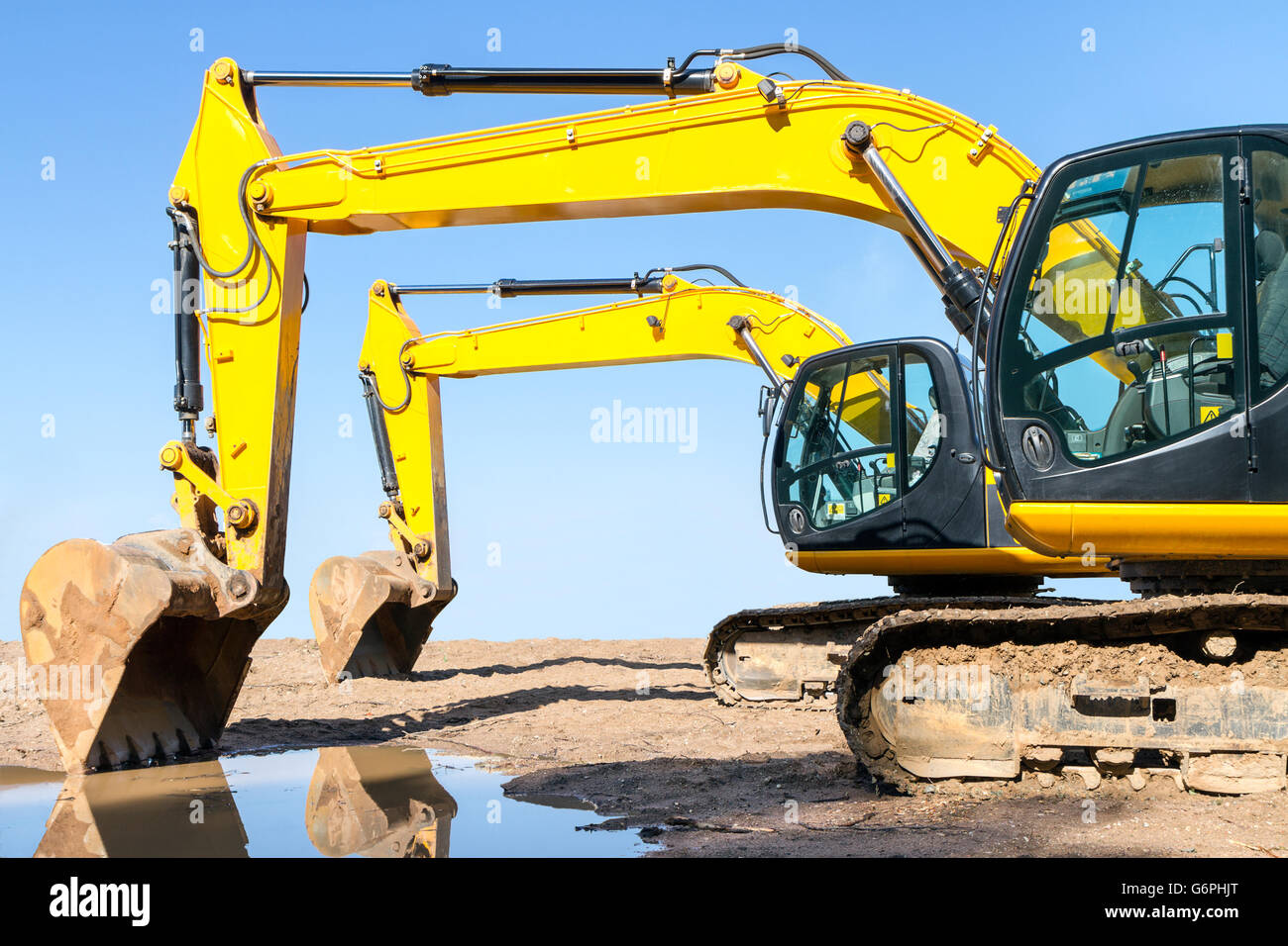 Yellow excavator on construction site against clear blue sky Stock Photo
