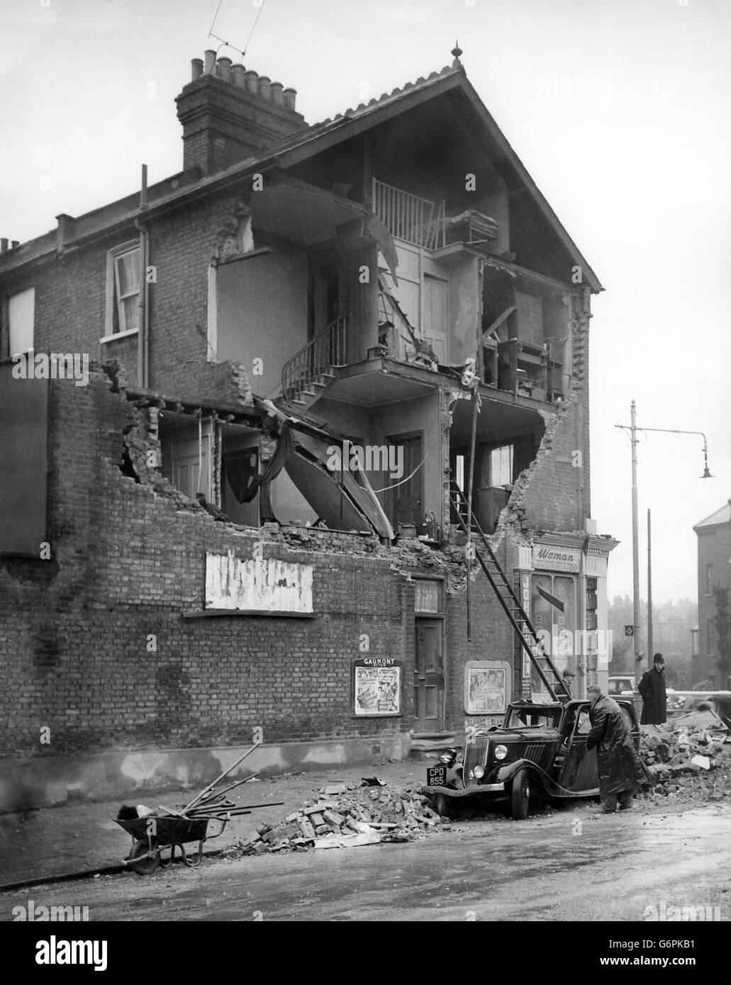 A policeman stands on duty as the work of clearing up the rubble continues outside an Acton house that was badly damaged by the whirlwind. In the road is a car battered by falling brickwork. Daylight revealed to Londoners the full extent of the damage caused during the night as the country was lashed by storms. Stock Photo