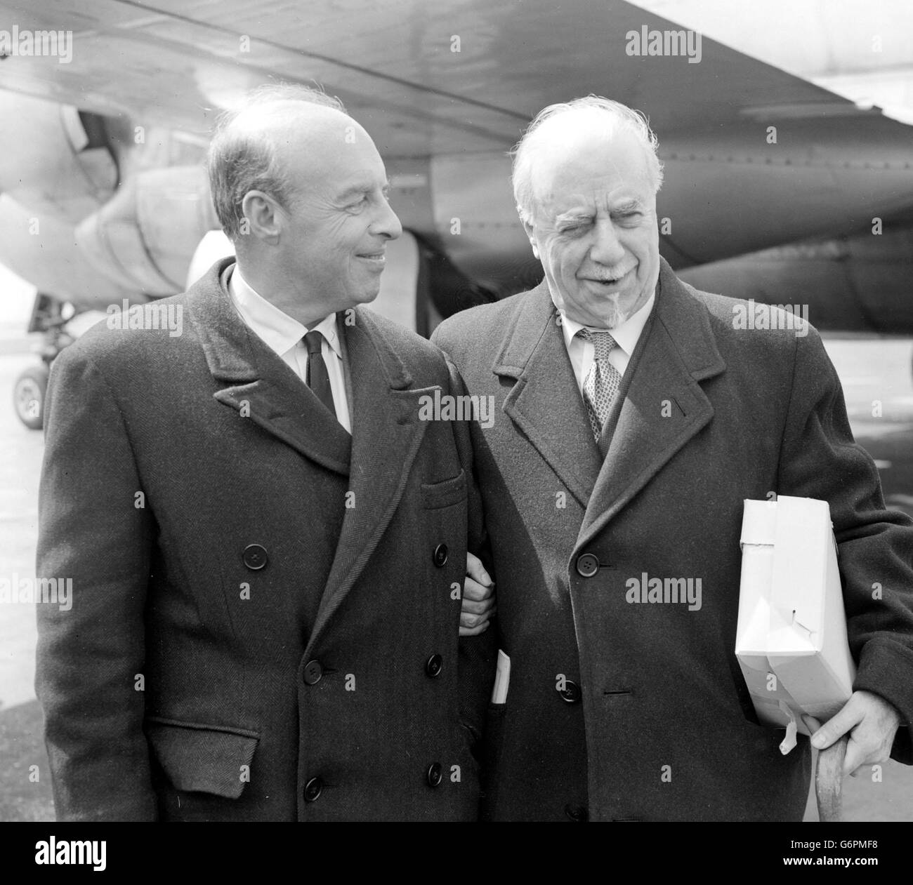 Happy fellow passengers on a BOAC liner from New York, American conductor Andre Kostelanetz (l) and British conductor Sir Thomas Beecham are pictured on their arrival at London Airport, on Sir Thomas's 77th birthday. Mr Kostelanetz (husband of operatic soprano Lily Pons) is to conduct the Royal Philharmonic Orchestra in a concert on BBC Television. Sir Thomas has returned from a short tour in the USA. Stock Photo
