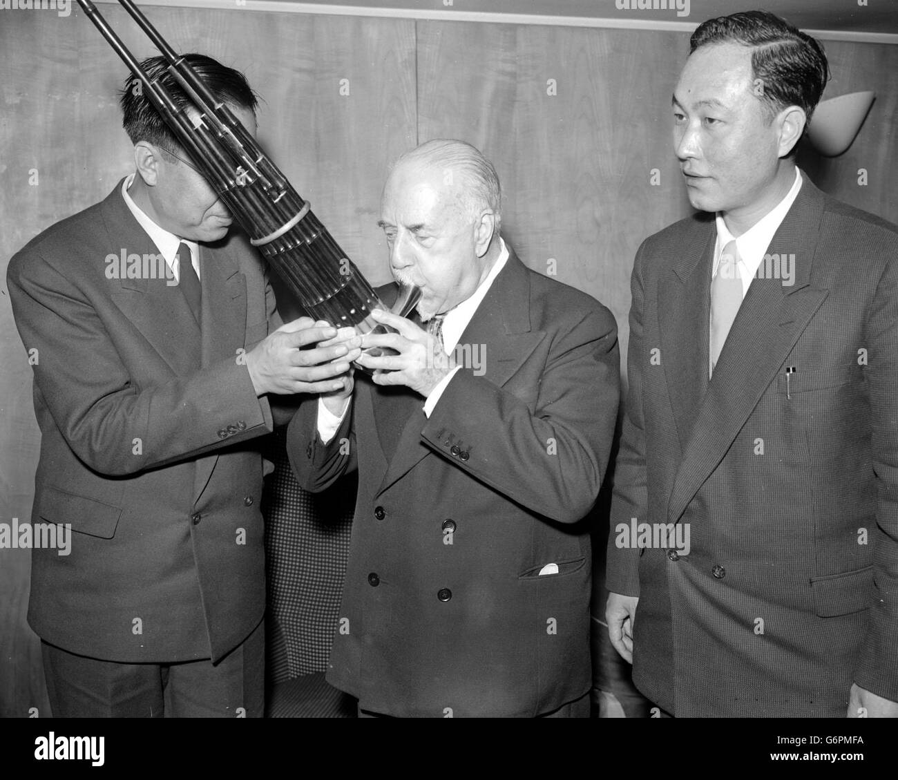 Sir Thomas Beecham takes time off from a rehearsal with the Royal Philharmonic Orchestra at London's Royal Festival Hall to try and coax a tune from a set of Chinese bagpipes, more correctly called 'sheng' had just been presented to him by members of the orchestra of the Variety Theatre of China. Stock Photo