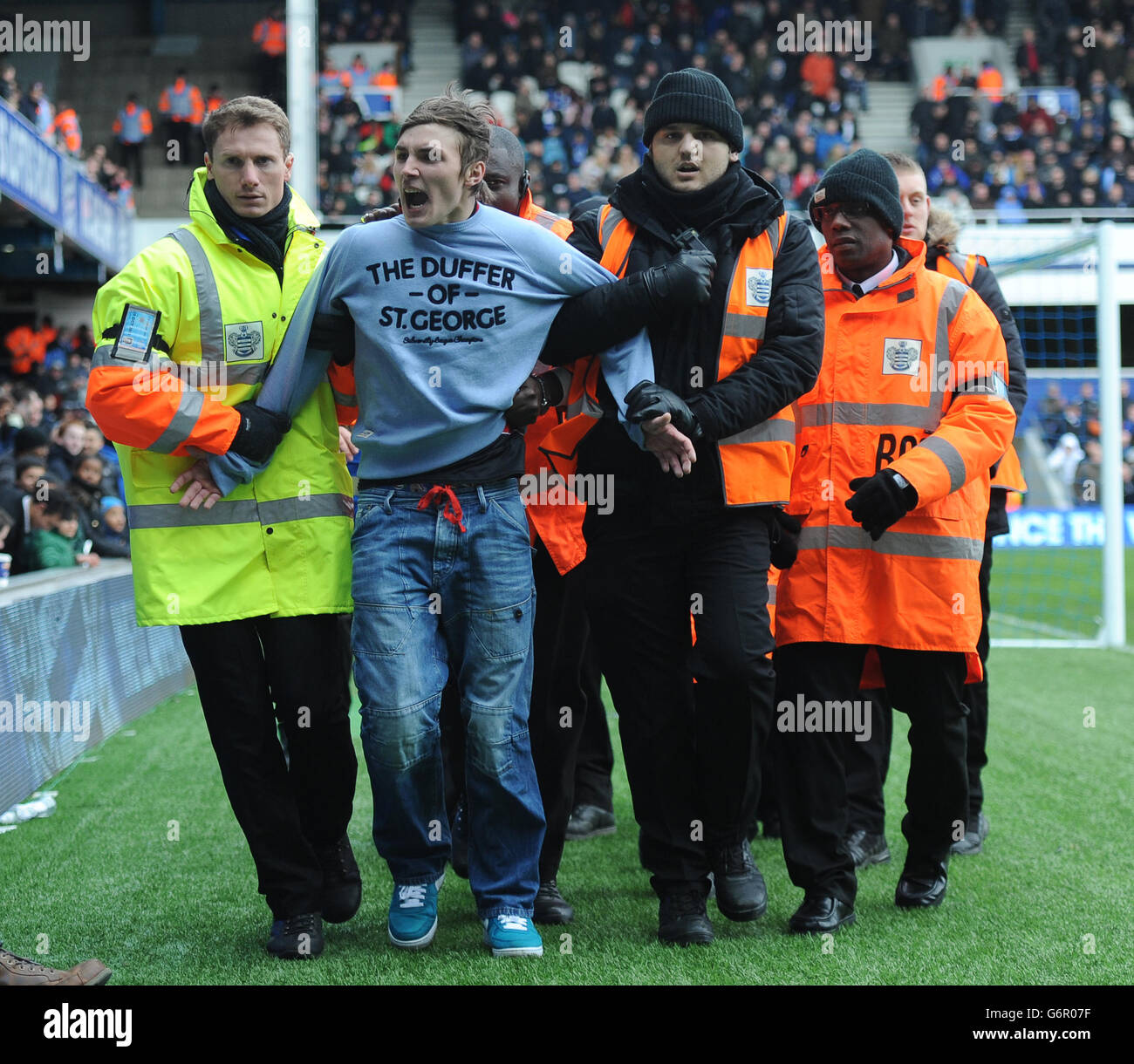 A Queens Park Rangers' fan who invaded the pitch is lead away by ...