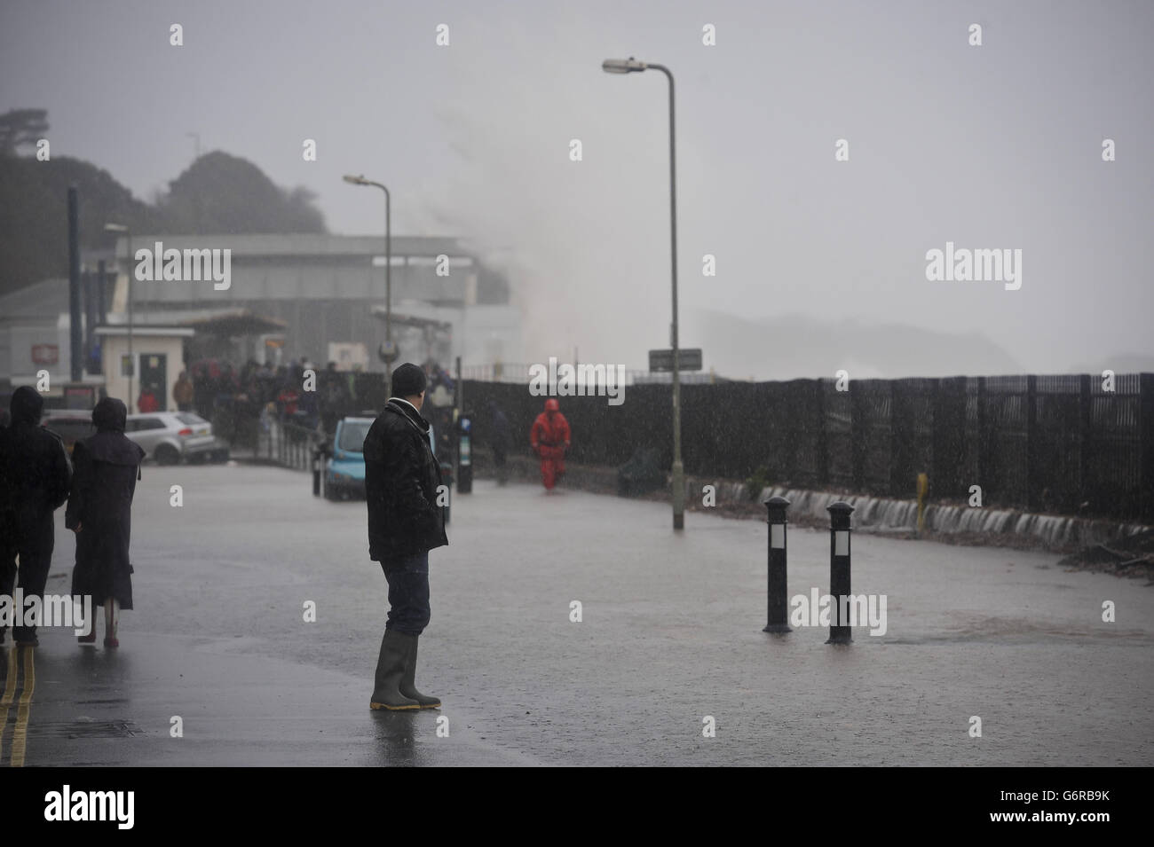 A man in the torrential rain in Dawlish, where high tides and strong winds have created havoc in the Devonshire town disrupting road and rail networks and damaging property. Stock Photo
