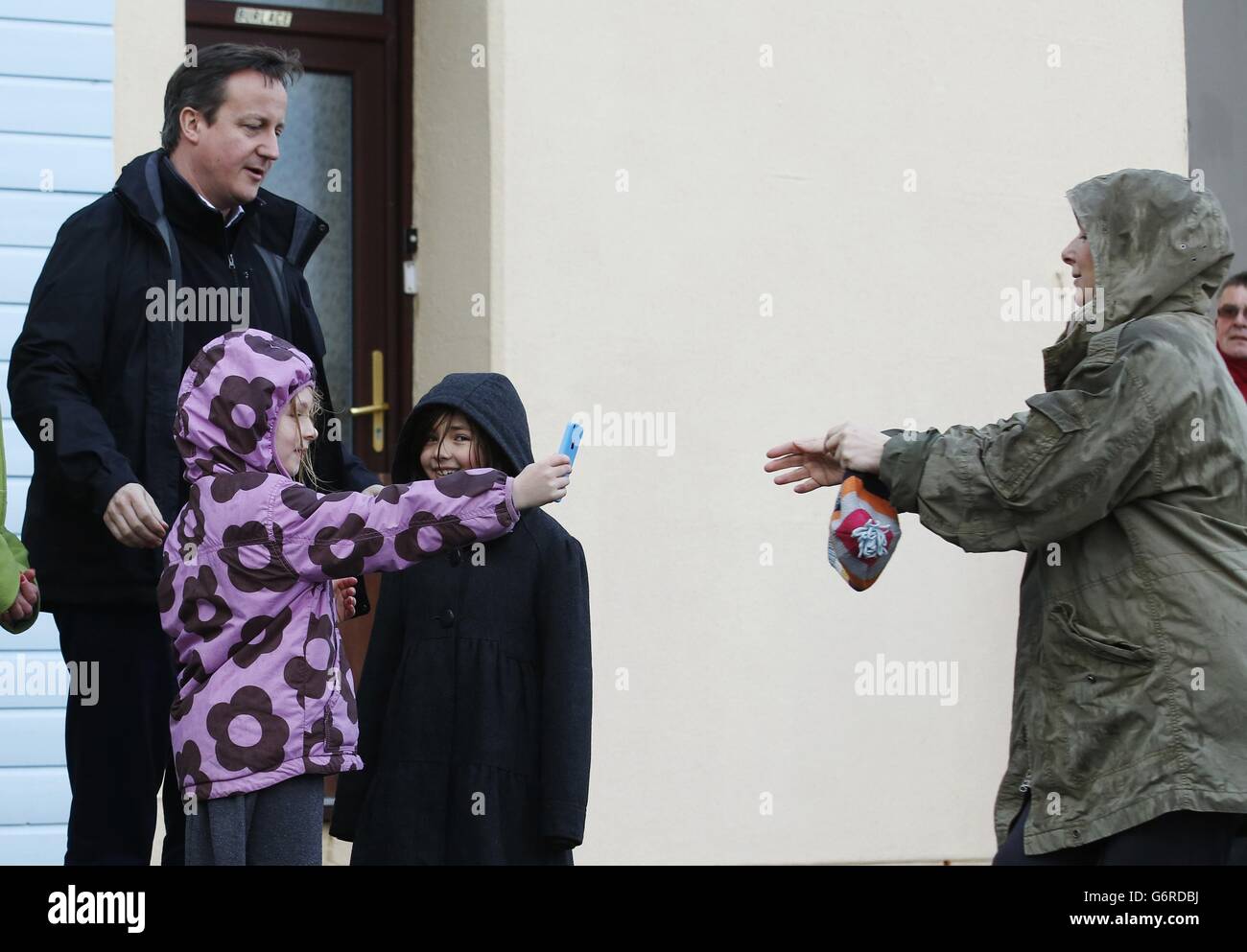 Prime Minister David Cameron (centre) and MP Sheryll Murray speak to a local residnet whose home was damaged during recent storms in Kingsand in Cornwall. Stock Photo