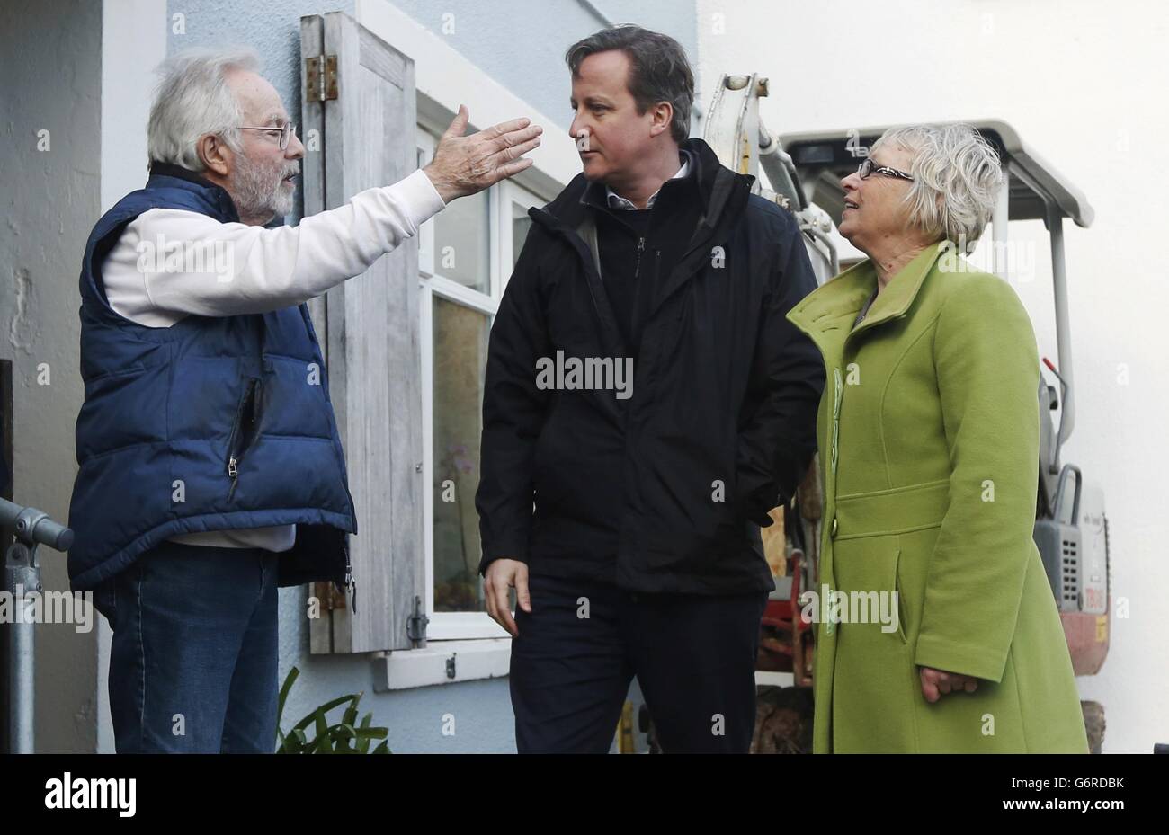 Prime Minister David Cameron (centre) and MP Sheryll Murray speak to a local residnet whose home was damaged during recent storms in Kingsand in Cornwall. Stock Photo